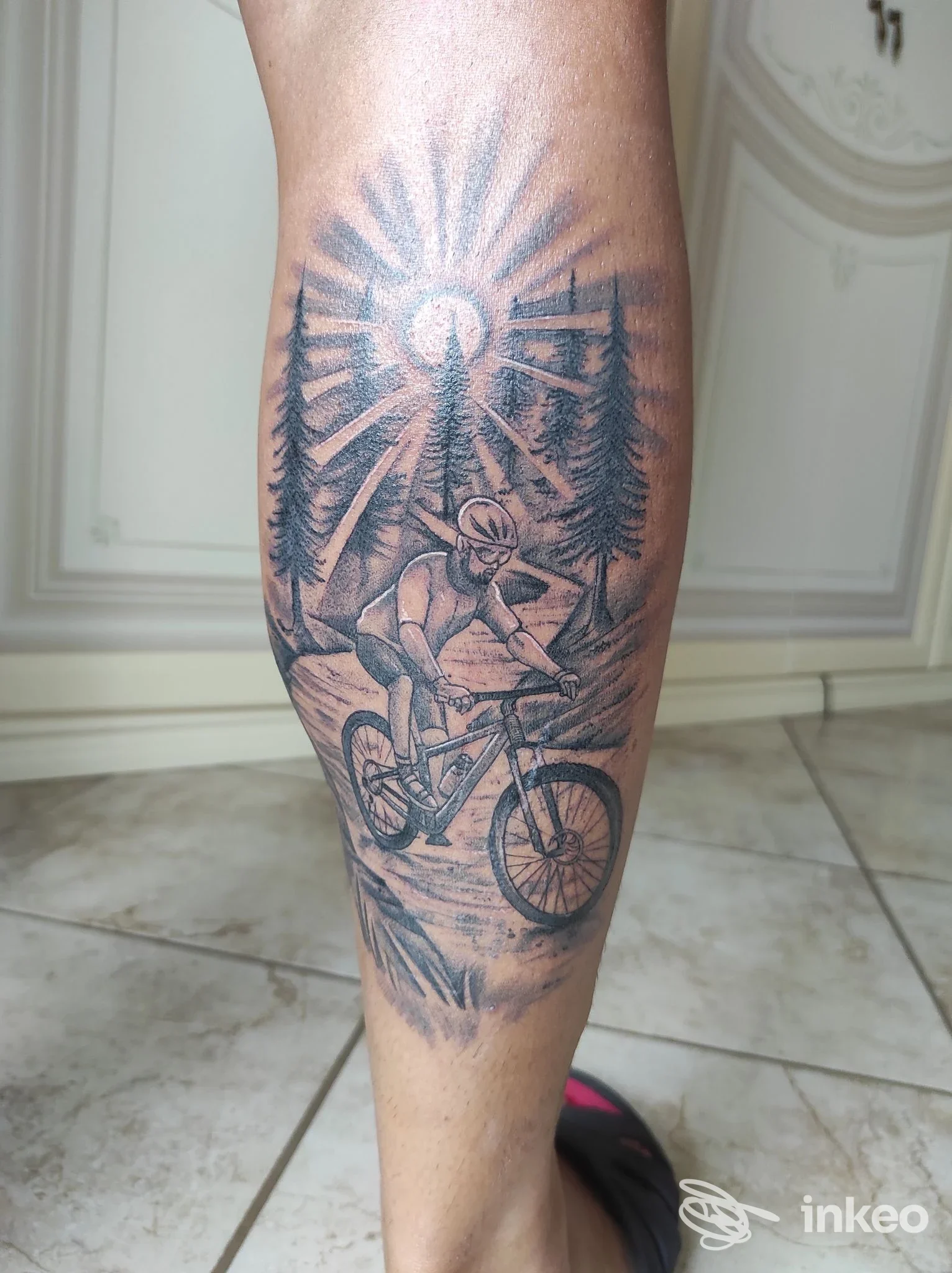 Tatuaggio su polpaccio con ciclista in mountain bike tra gli alberi, realizzato da Old Fishermen Tattoo a Martina Franca.