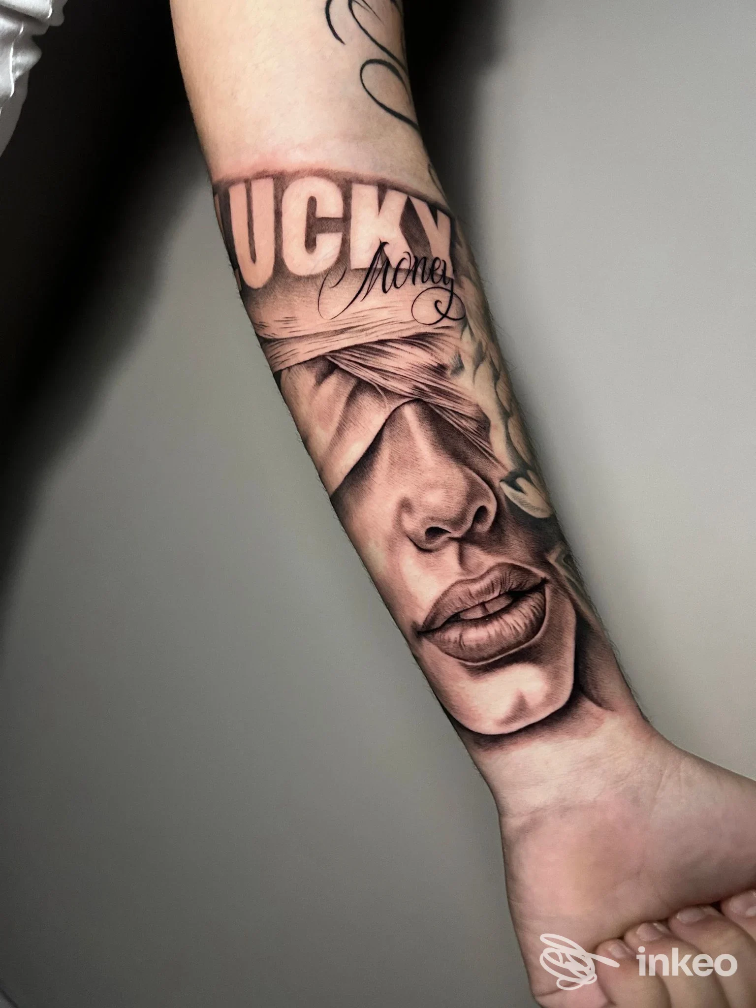 Tatuaggio realistico in bianco e nero su avambraccio con volto bendato e scritta parziale, REEDA TATTOO, San Severo.