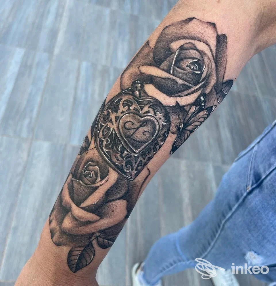 Tattoo realistico con rose e medaglione sull'avambraccio, fotografato per RG Tattoo Studio a San Severo.