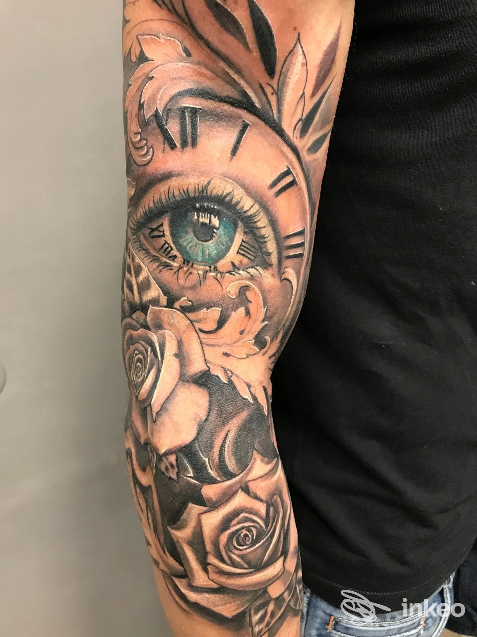 Manica parziale su avambraccio con rose, decori ornamentali e un occhio realistico colorato, Oldskulltattoo, Erchie.