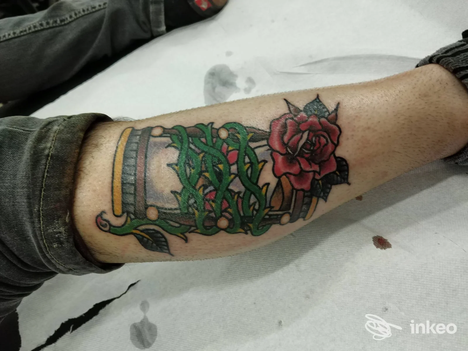 Tatuaggio su avambraccio raffigurante una clessidra avvolta da edera e una rosa rossa, Simone Art Tattoo, Bari.