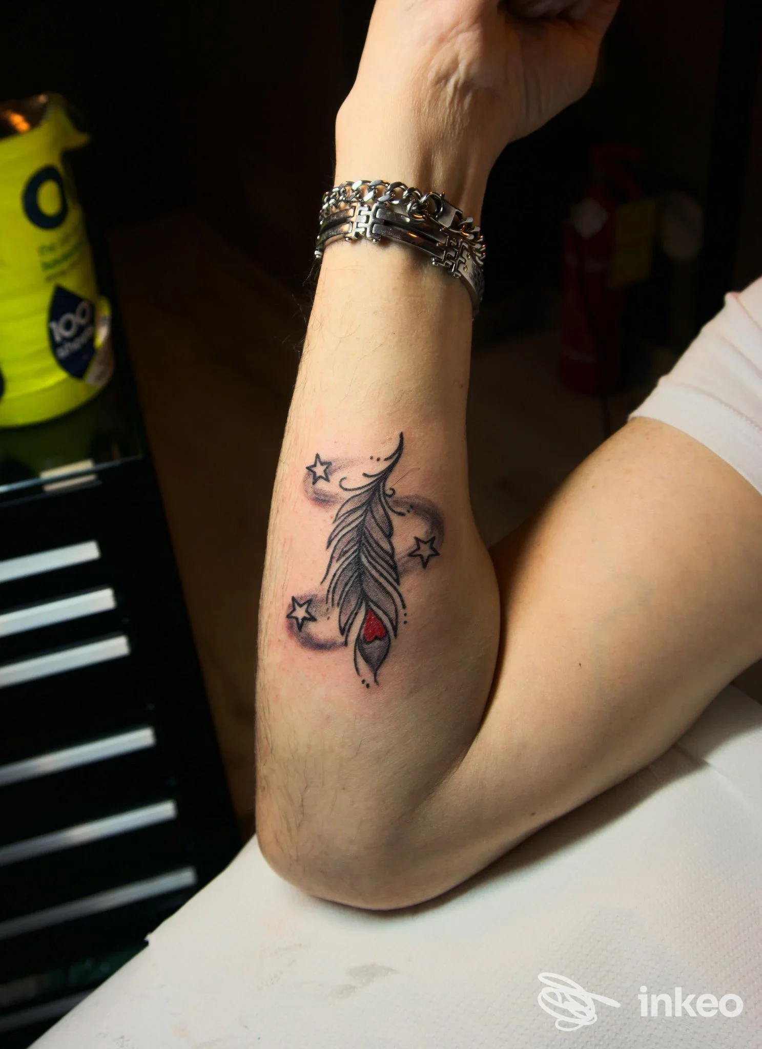 Primo piano di un avambraccio tatuato con una piuma stilizzata e stelle, Smaya Tattoo, San Severo.
