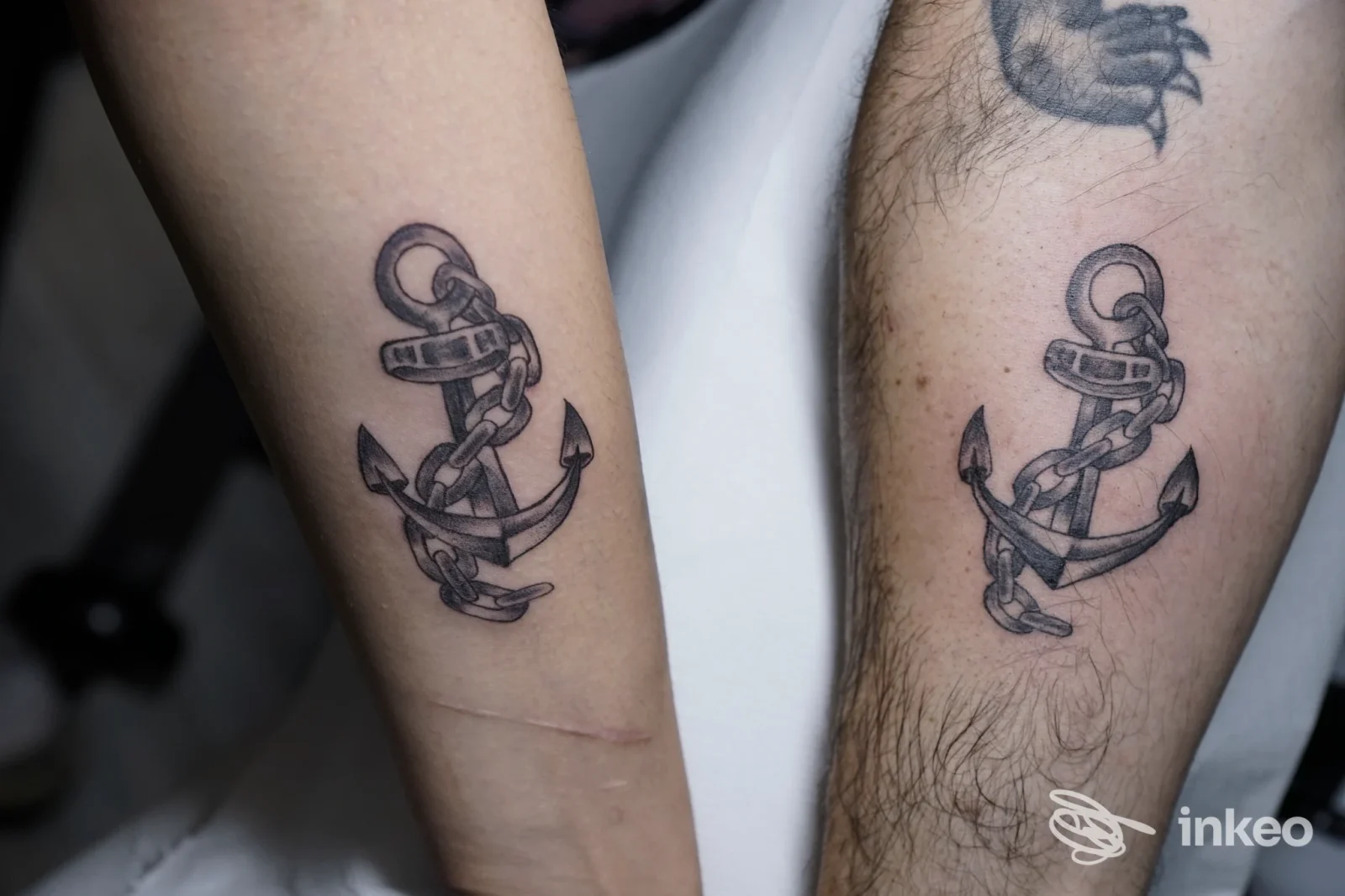 Due avambracci con lo stesso tatuaggio ancora e catena in nero, foto per Smaya Tattoo a San Severo.