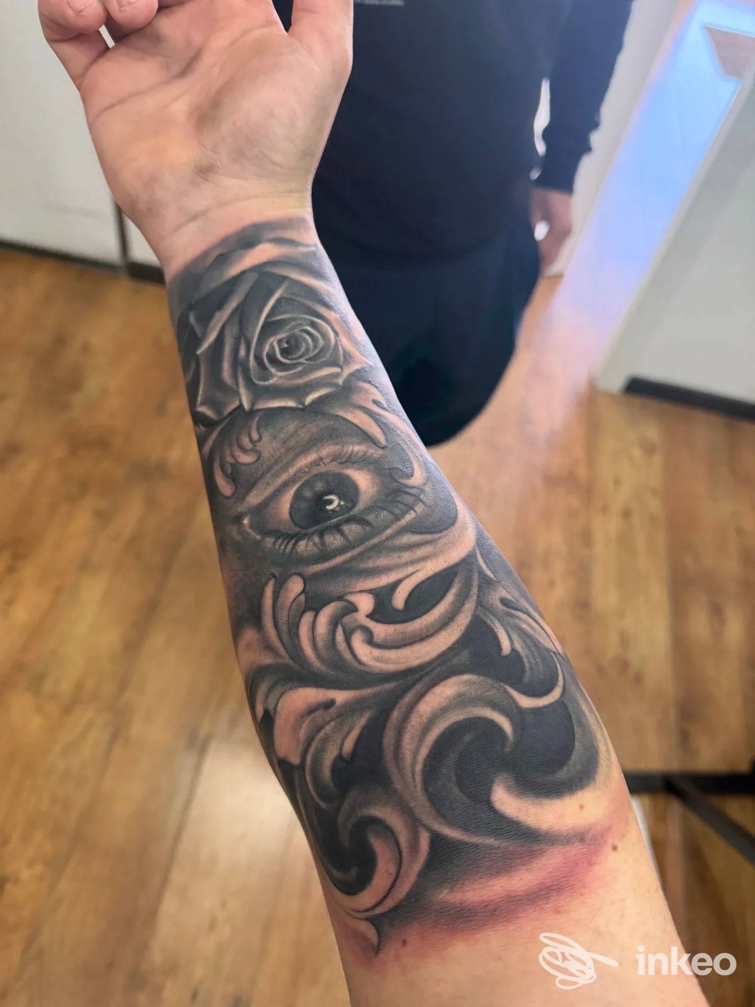 Avambraccio tatuato in bianco e nero con rosa, occhio realistico e decorazioni, foto per Steven Tattoo Artist a Mesagne.