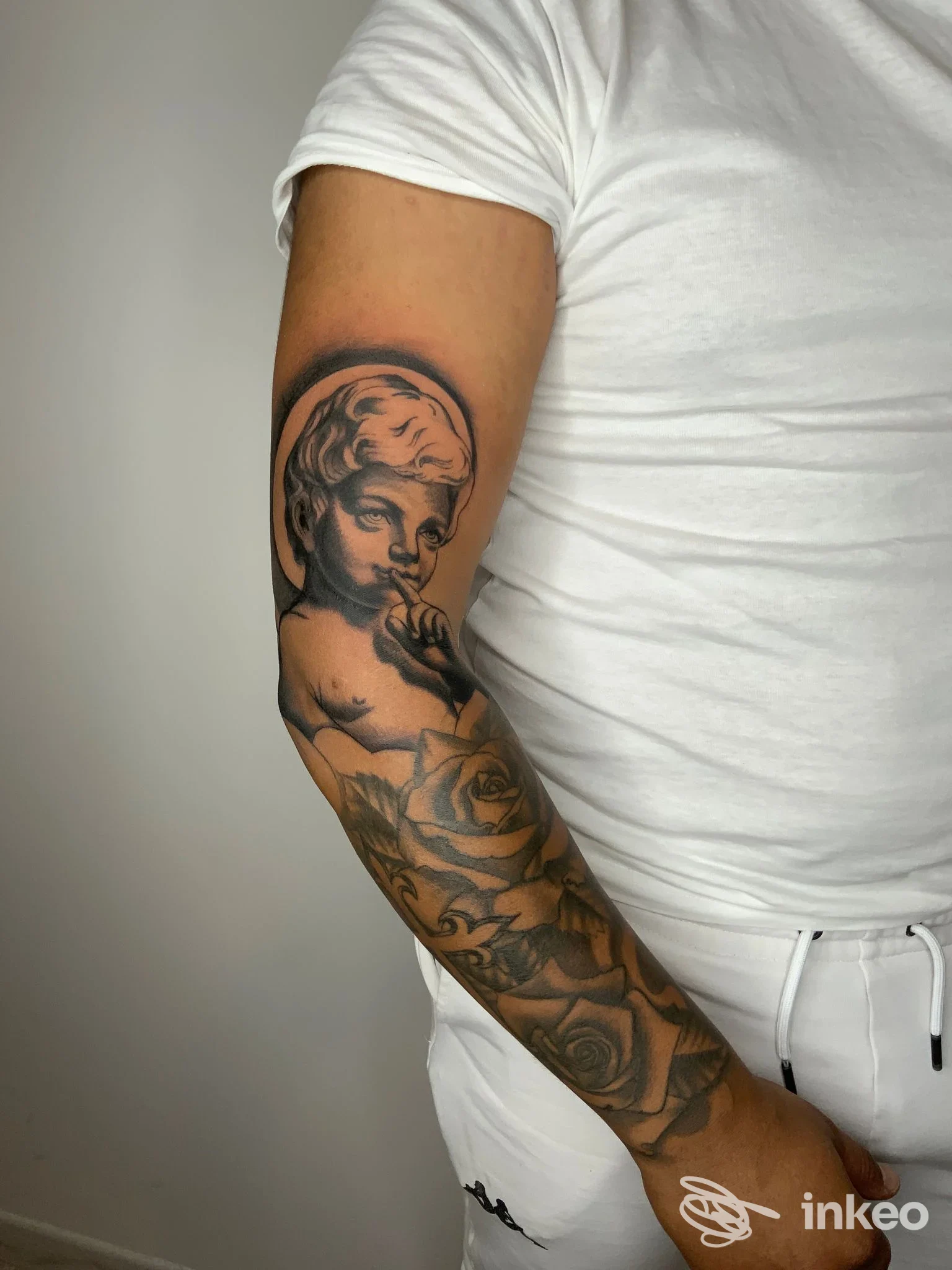 Manica tatuata in bianco e nero con cherubino e rose, foto inviata da Tarantula Tattoo Studio, Accadia.