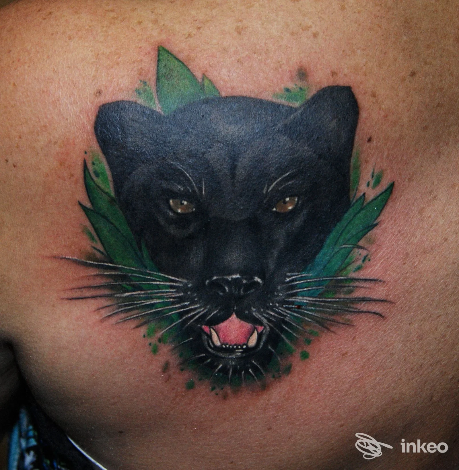 Tatuaggio di una testa di pantera nera con foglie verdi sul pettorale, realizzato da Tattoo Wave di Di Luzio Marco, Taranto.