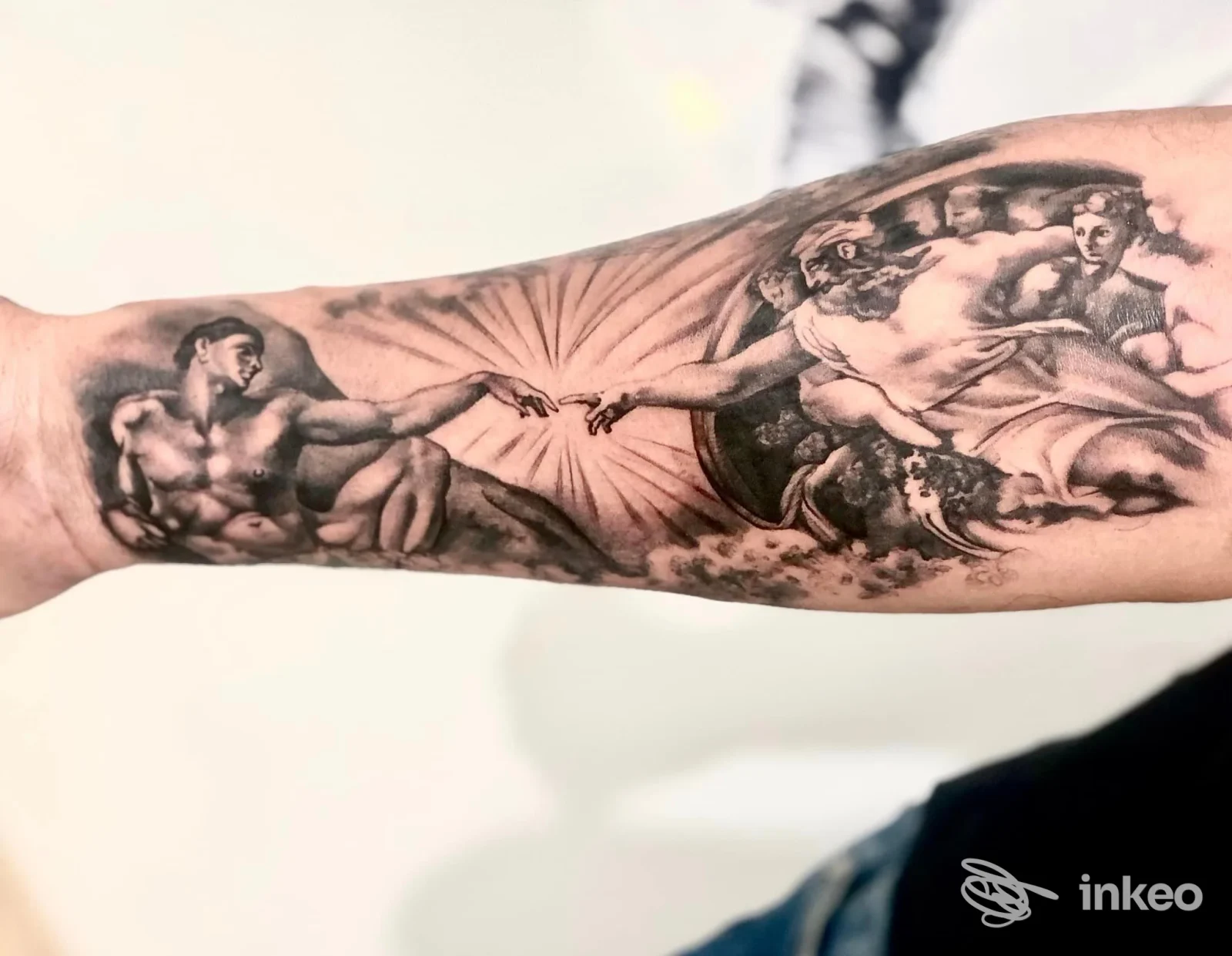 Tatuaggio realistico a inchiostro nero sull'avambraccio, replica figurativa della Creazione di Adamo — Bloodline Tattoo, Manduria.