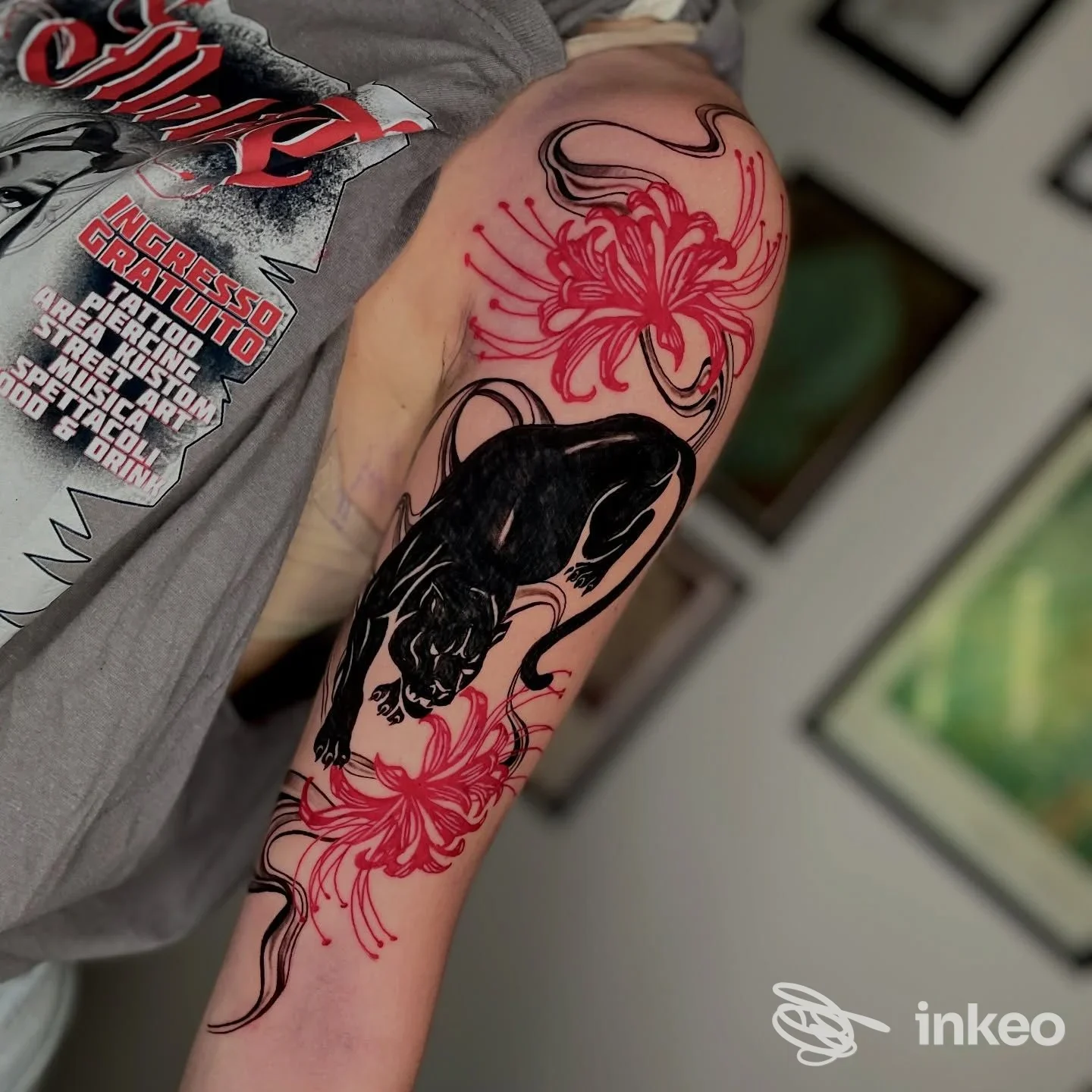 Tatuaggio sul braccio superiore presso Tatuaggeria a Castellana Grotte: pantera nera stilizzata accompagnata da fiori rossi.