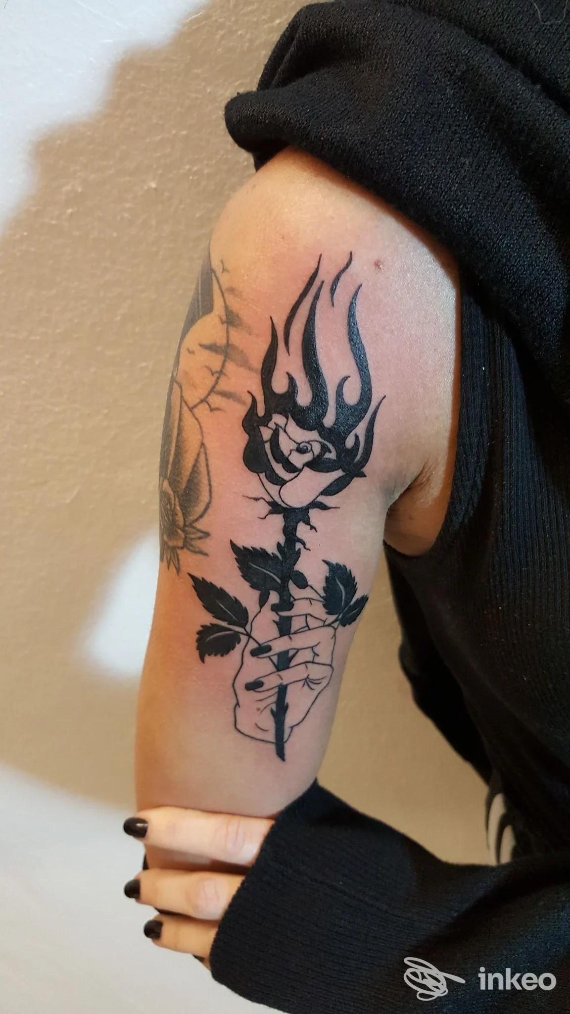 Tatuaggio nero sul braccio superiore: rosa fiammeggiante con mano, fotografato per Work Hard Barber Shop And Tattoo a Casarano.
