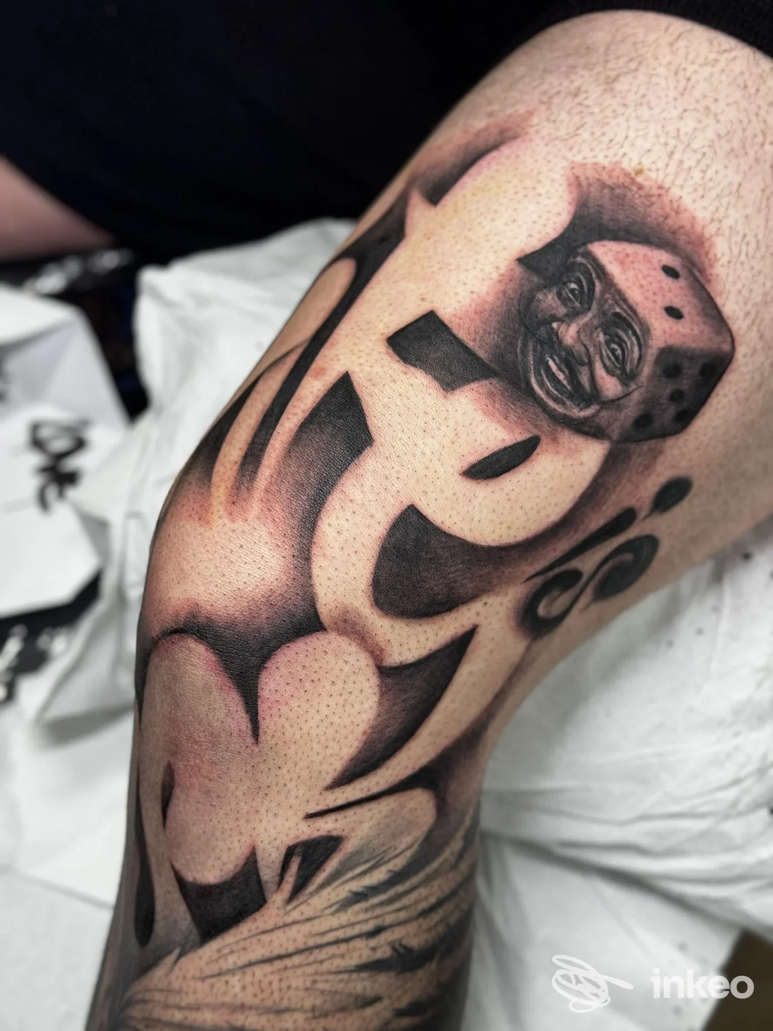 Tatuaggio nero e grigio su coscia con ampie aree negative e un piccolo dado tatuato con volto, foto per studioz - Tattoo Design, Triggiano.