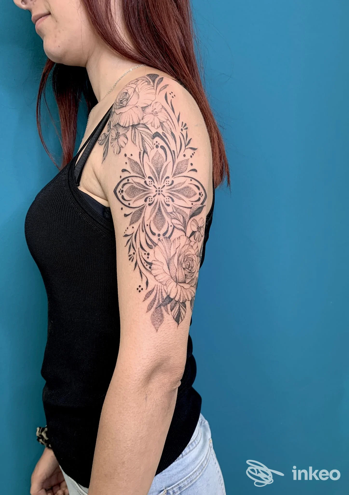 Primo piano di un tatuaggio floreale ornamentale sull'omero di una donna, foto fornita da Supersonic Tattoo Studio, Alghero.