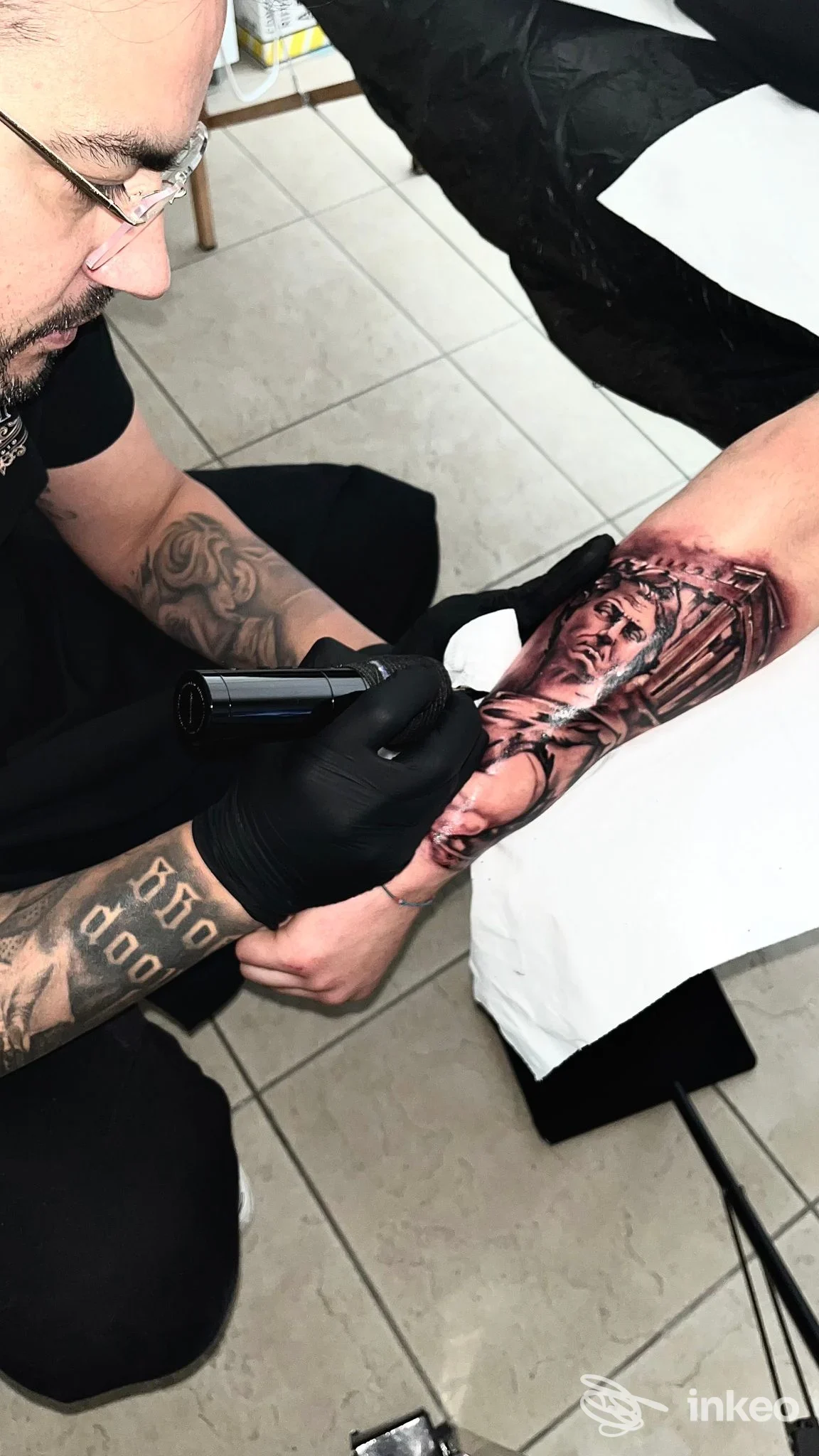 Tatuatore al lavoro sull'avambraccio di un cliente nello studio Tattoo Studio Mauro Pani a Villaspeciosa.