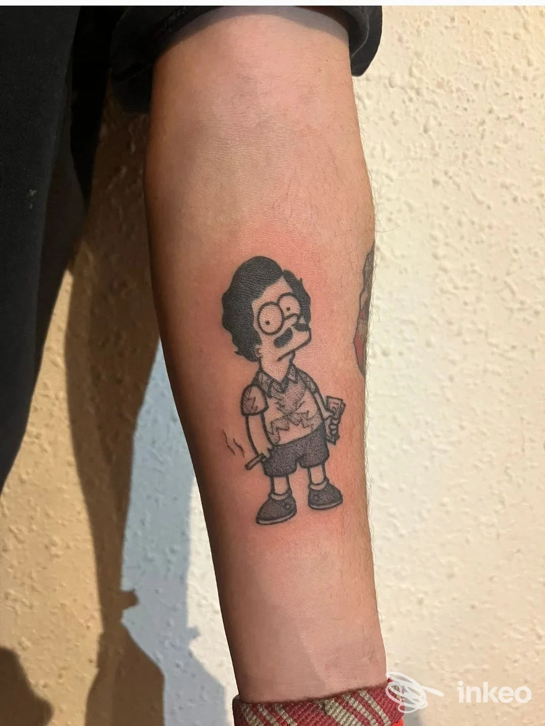 Tatuaggio in bianco e nero di un personaggio in stile cartone sull'avambraccio, realizzato da Tattoo house a Cala Caterina.