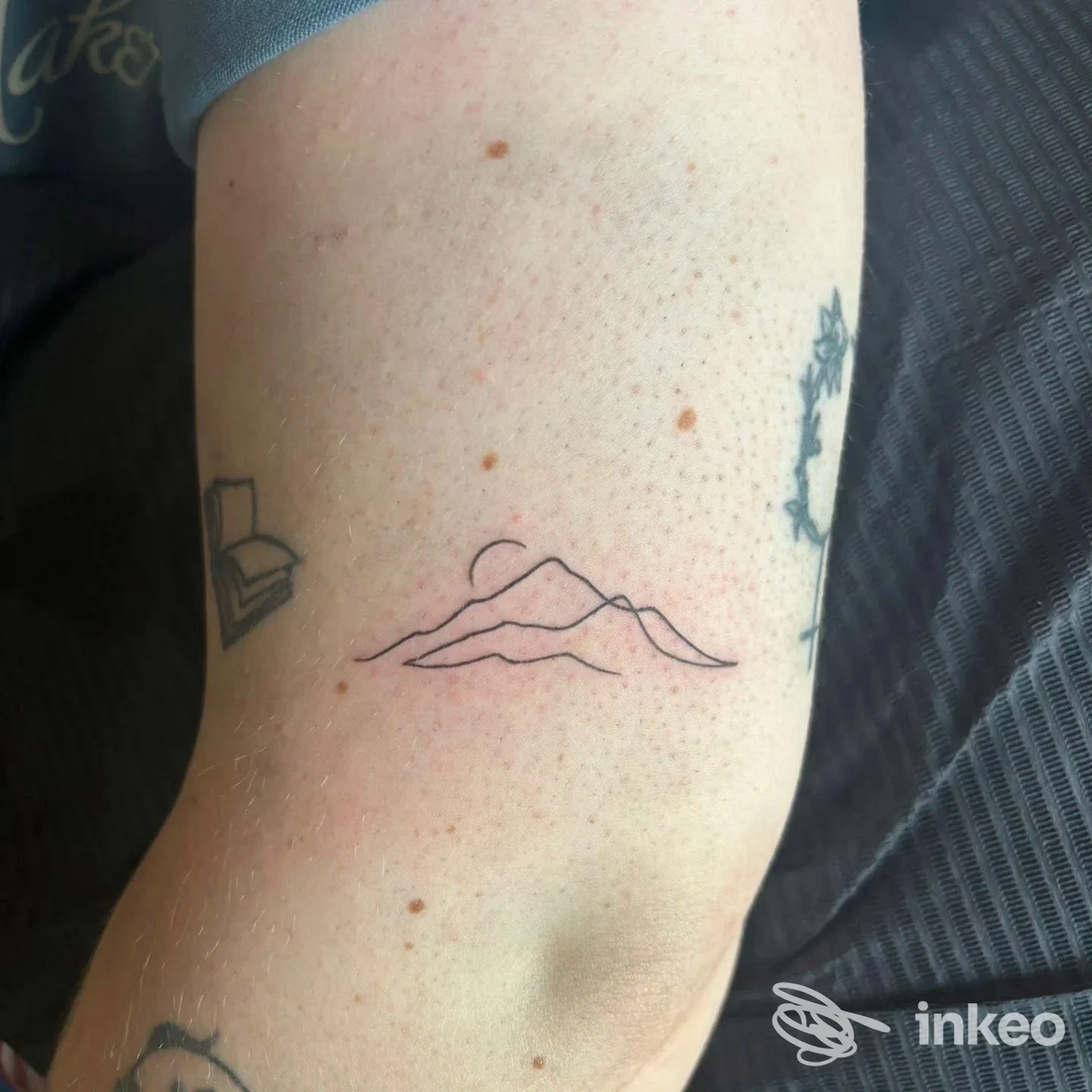 Piccolo tatuaggio lineare di montagne sull'avambraccio, realizzato da Tattoo house a Cala Caterina.