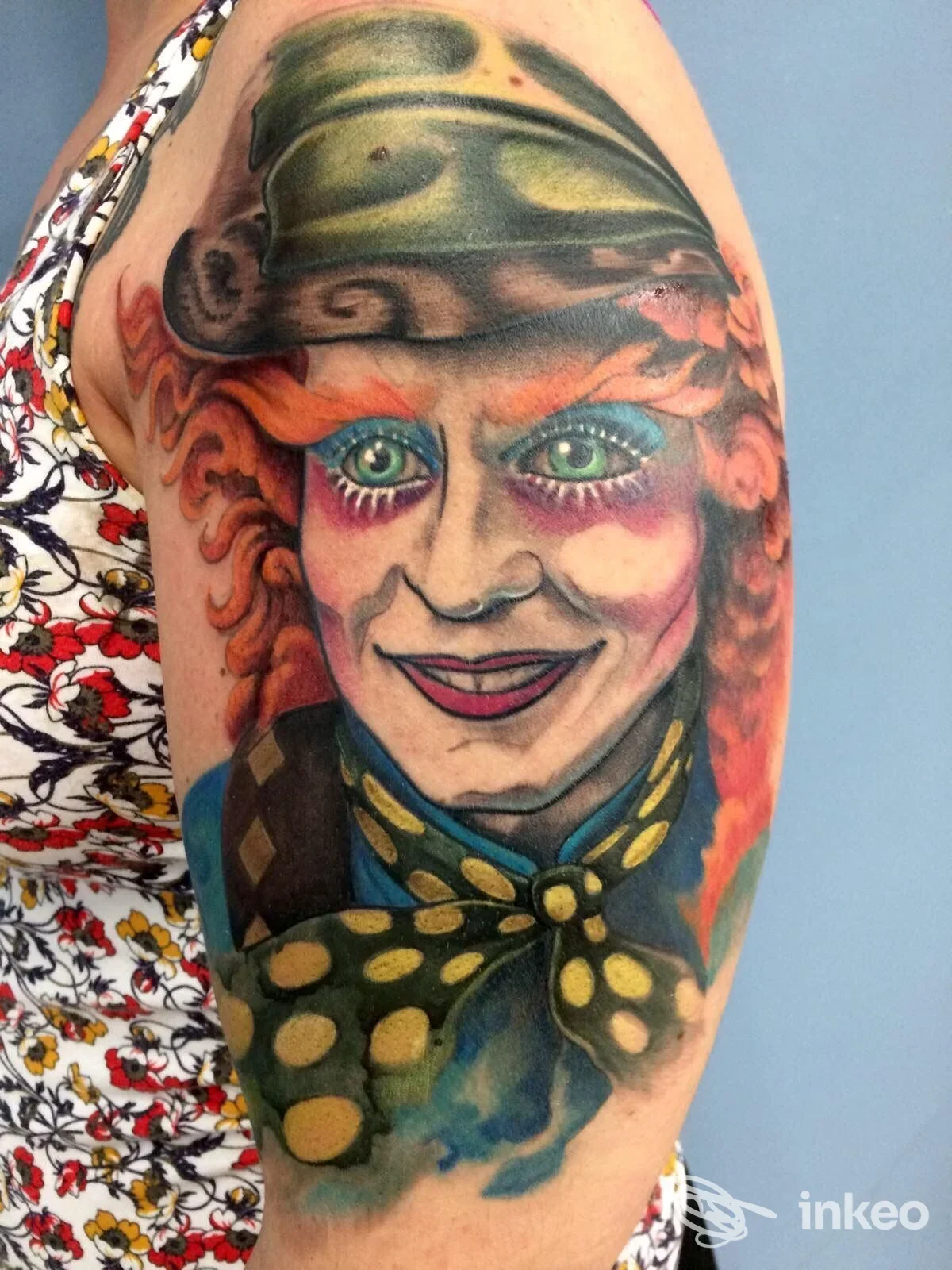 Tatuaggio a colori sul braccio superiore raffigurante un volto con cappello e fiocco — Stigma Tattoo, Porto Torres
