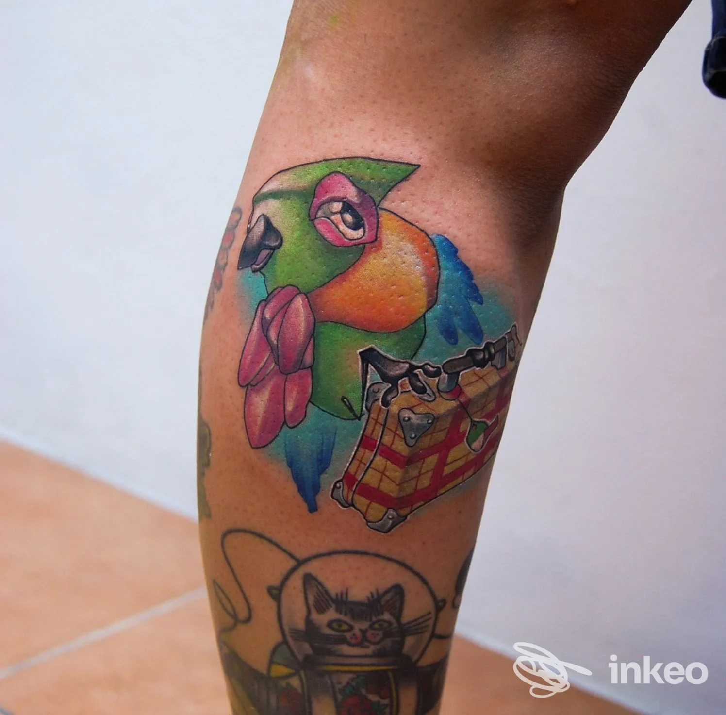 Tatuaggio colorato a pappagallo e altri motivi sul polpaccio, fotografia per T'ink tattoo studio ad Alghero.