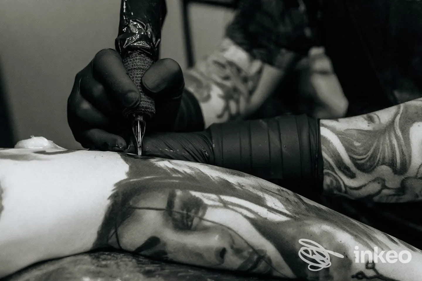 Tatuatore di AVM Tattoos and Tarot a Selargius al lavoro su un ritratto realistico in nero su avambraccio, primo piano della sessione.