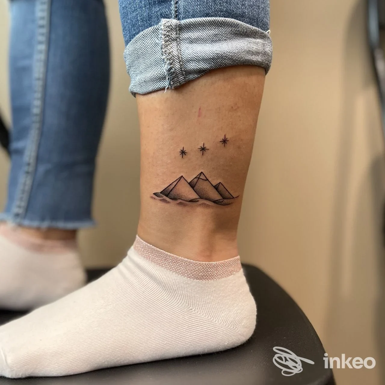 Tatuaggio minimal di montagne e quattro stelle sulla caviglia, fotografato nello studio Alaff_Art Tattoo Studio a Macomer.