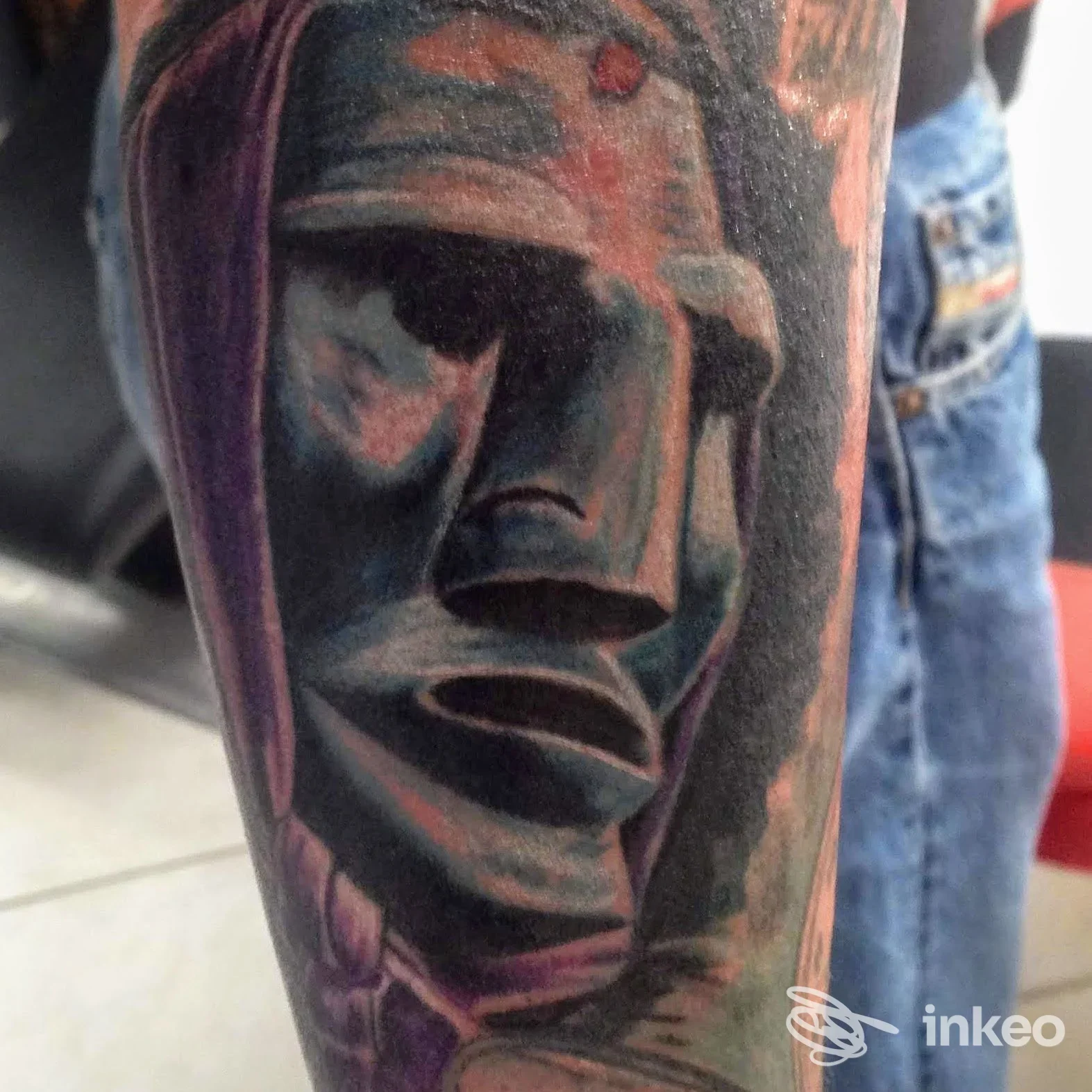 Primo piano di un tatuaggio realistico raffigurante un volto stilizzato sull'avambraccio, realizzato presso axis tatuaggi e body piercing a Sestu.