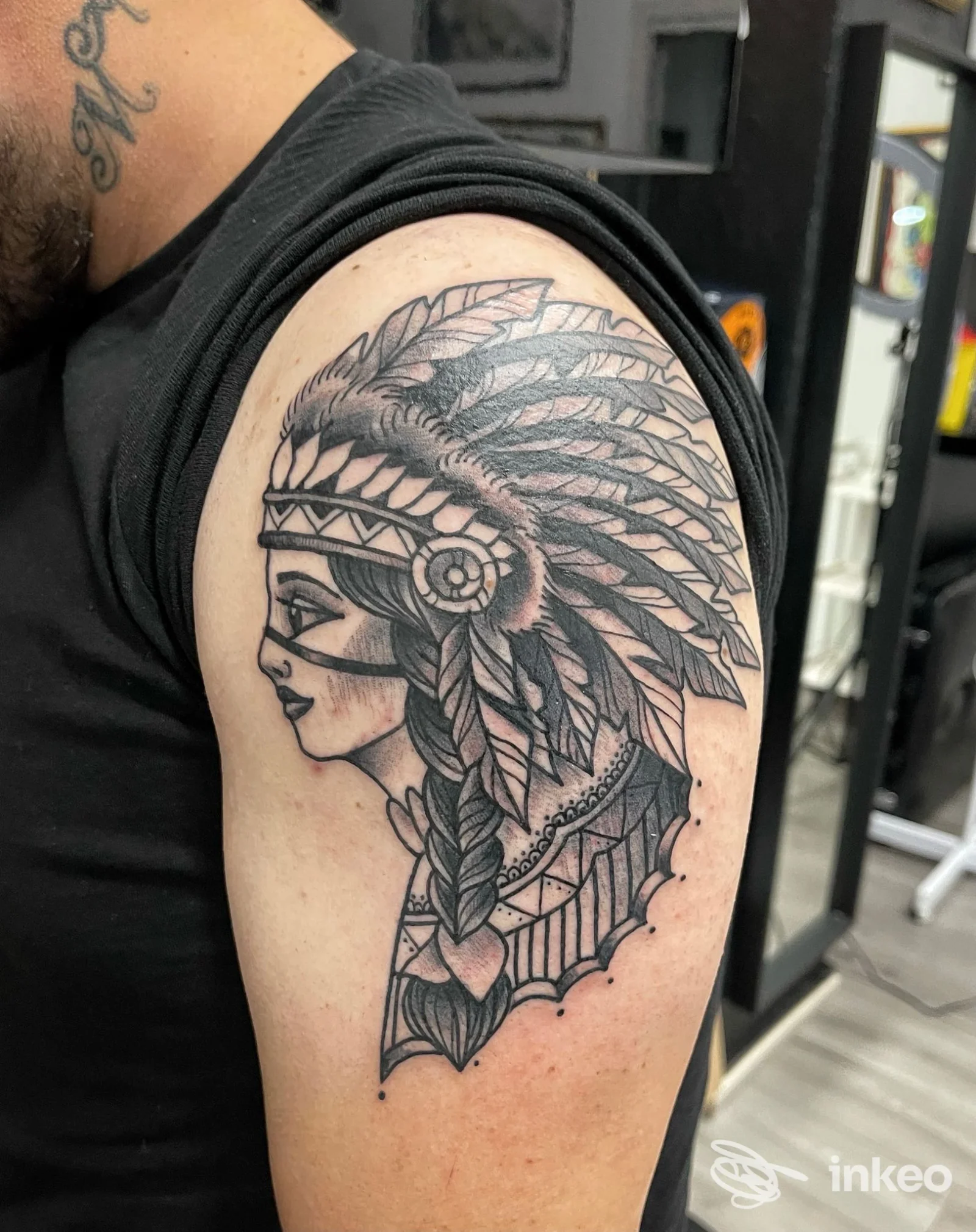 Tatuaggio black-and-grey di profilo femminile con copricapo di piume sul braccio superiore, 379 tattoo studio, Cagliari.