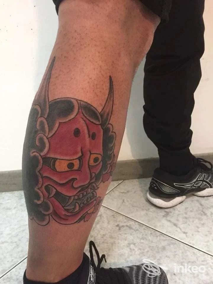 Grande tatuaggio a maschera Oni colorata sul polpaccio di un cliente, fotografato nello studio Battle Tattoo a Cagliari.