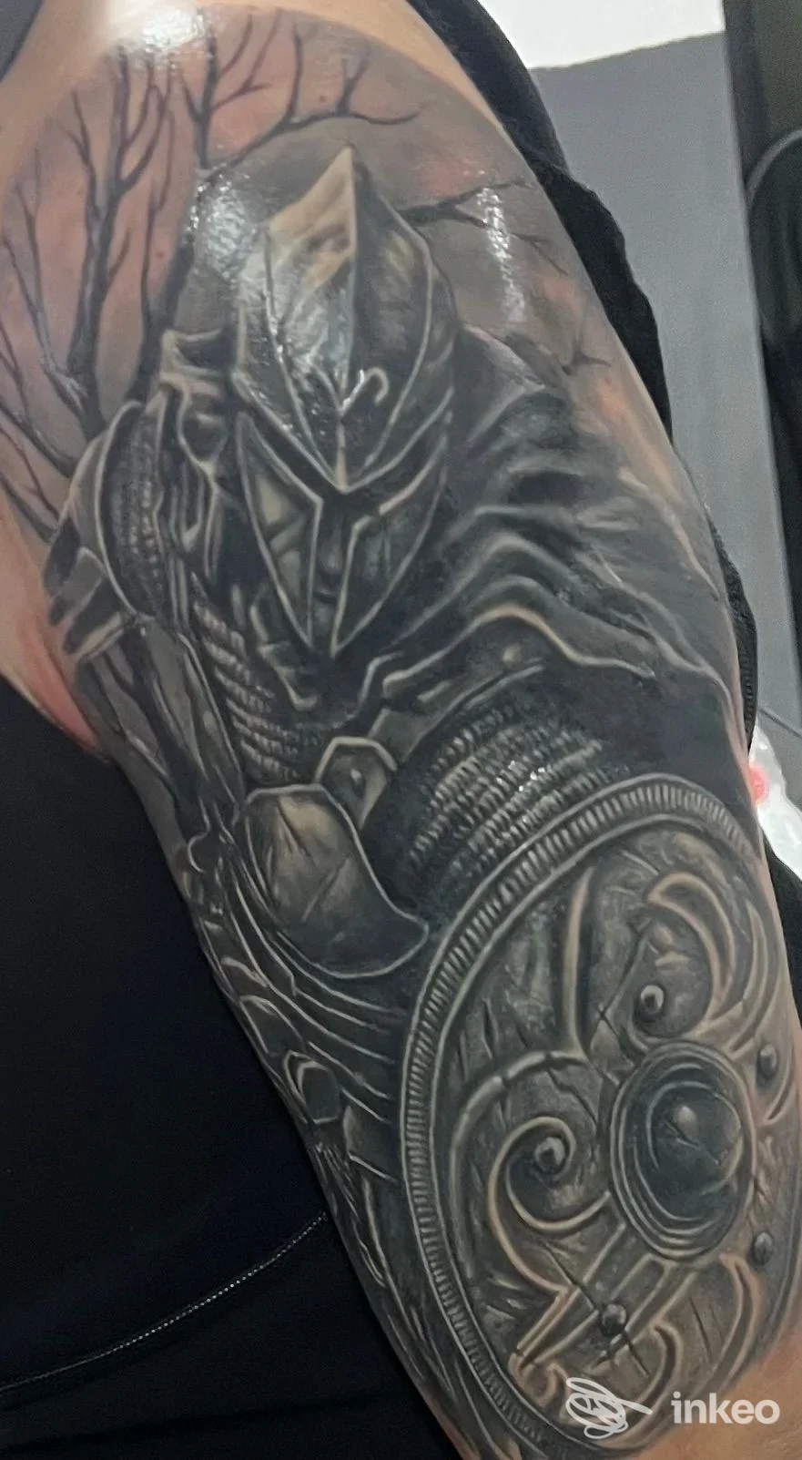 Tatuaggio in bianco e nero di un cavaliere con scudo sul braccio superiore, Black Apple tattoo studio, La Caletta.