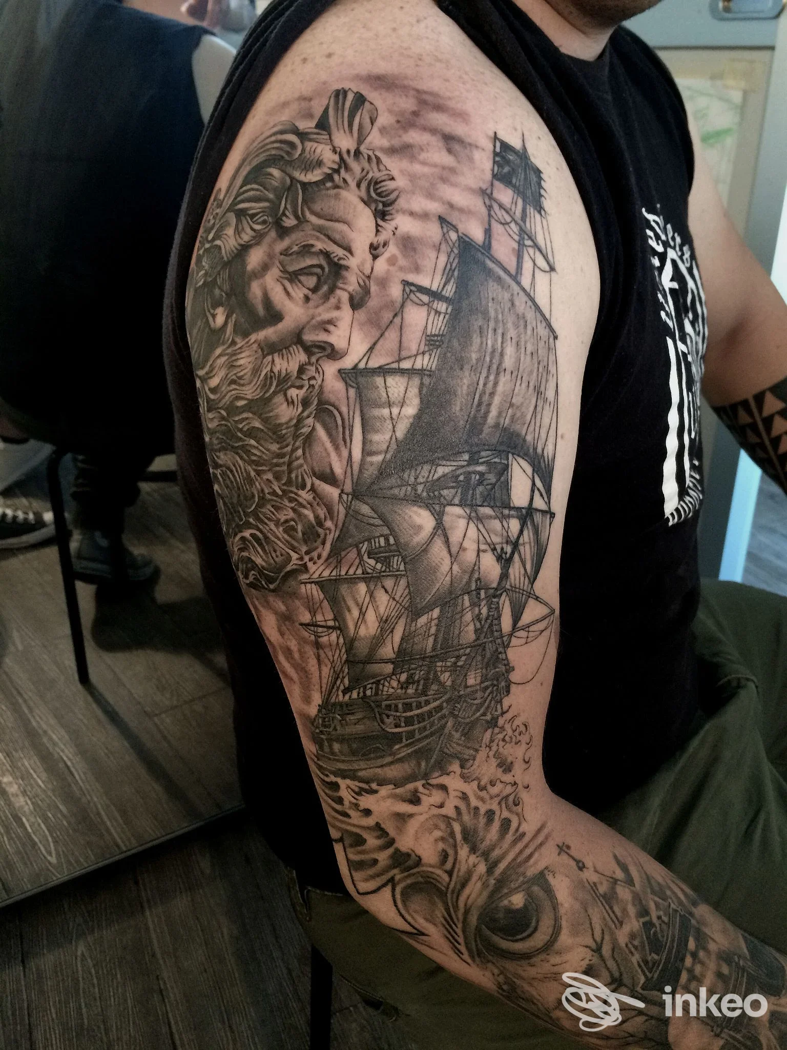 Tatuaggio su braccio visibile: veliero a vele fitte in stile realistico, con dettagli di mare e figure marine, eseguito sulla pelle reale.