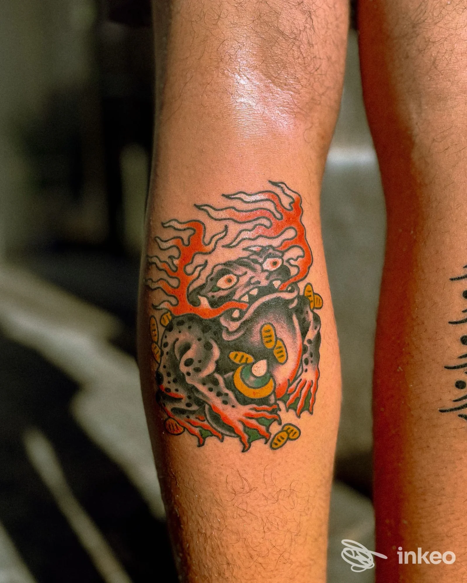 Tatuaggio colorato su polpaccio fotografato per Atelier Piercing & Tattoos, Cagliari, con figura stilizzata e colori vividi.