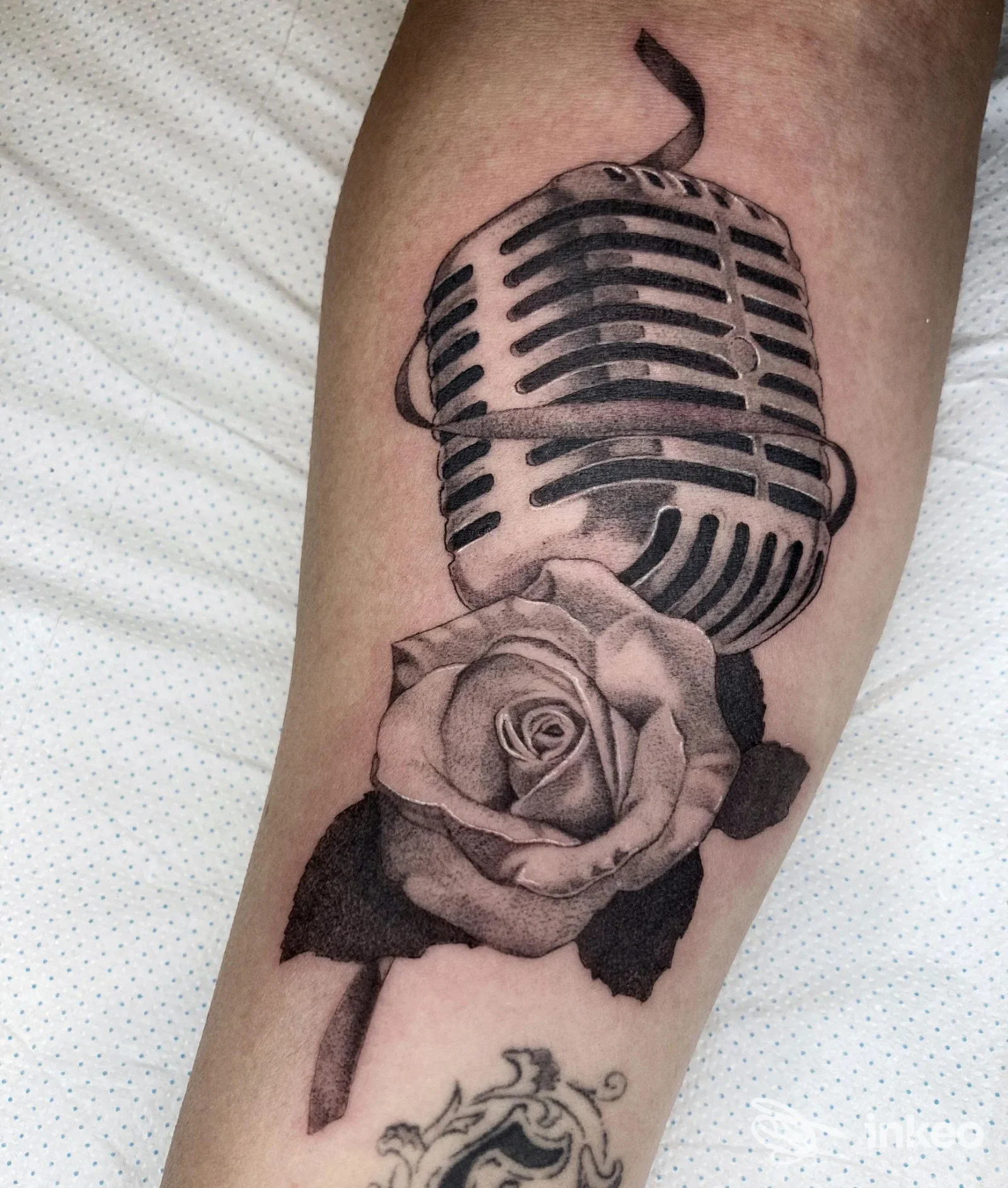 Tatuaggio in bianco e nero su avambraccio: microfono retrò sopra una rosa. Atelier Piercing & Tattoos, Cagliari.