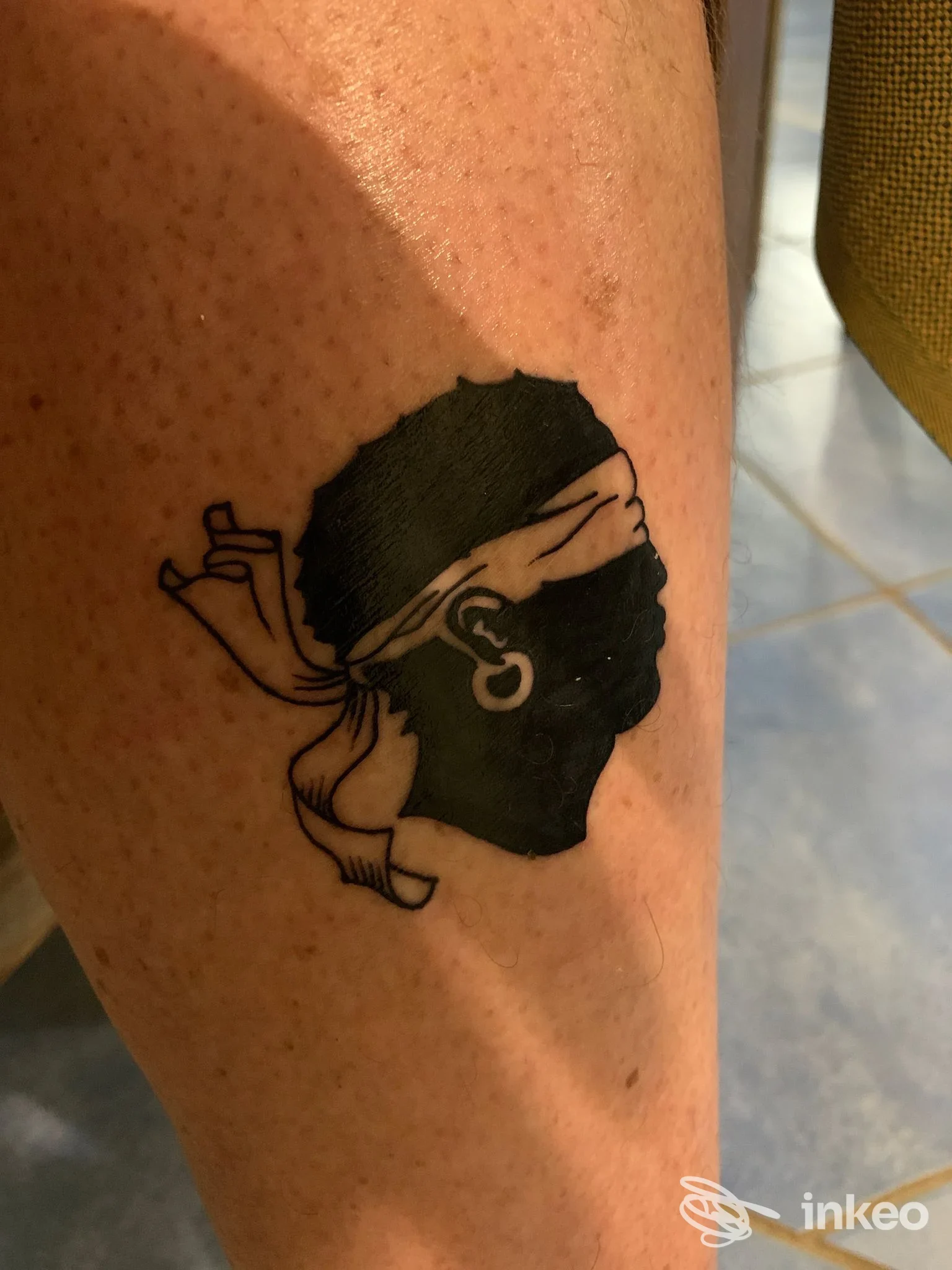 Tatuaggio a silhouette di una testa bendata sul polpaccio, eseguito da Black Mamba Tattoo Shop ad Alghero.