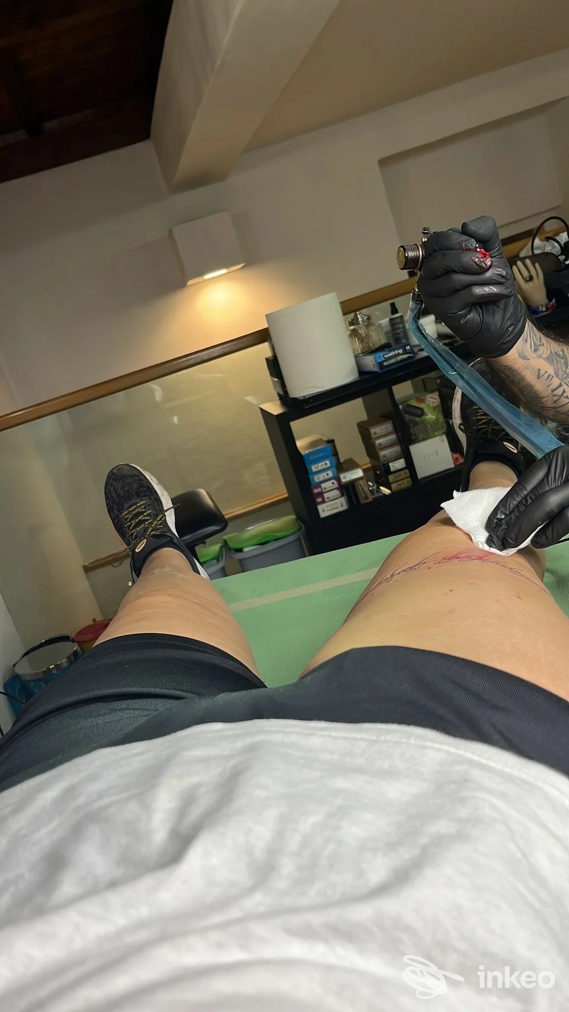 Fotografia in studio: tatuatore al lavoro sulla coscia di un cliente presso Black Mamba Tattoo Shop, Alghero.