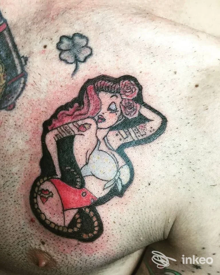 Tatuaggio pin-up sul petto eseguito da Black Sails Tattoo Studio a Selargius, figura stilizzata con dettagli rossi e neri.