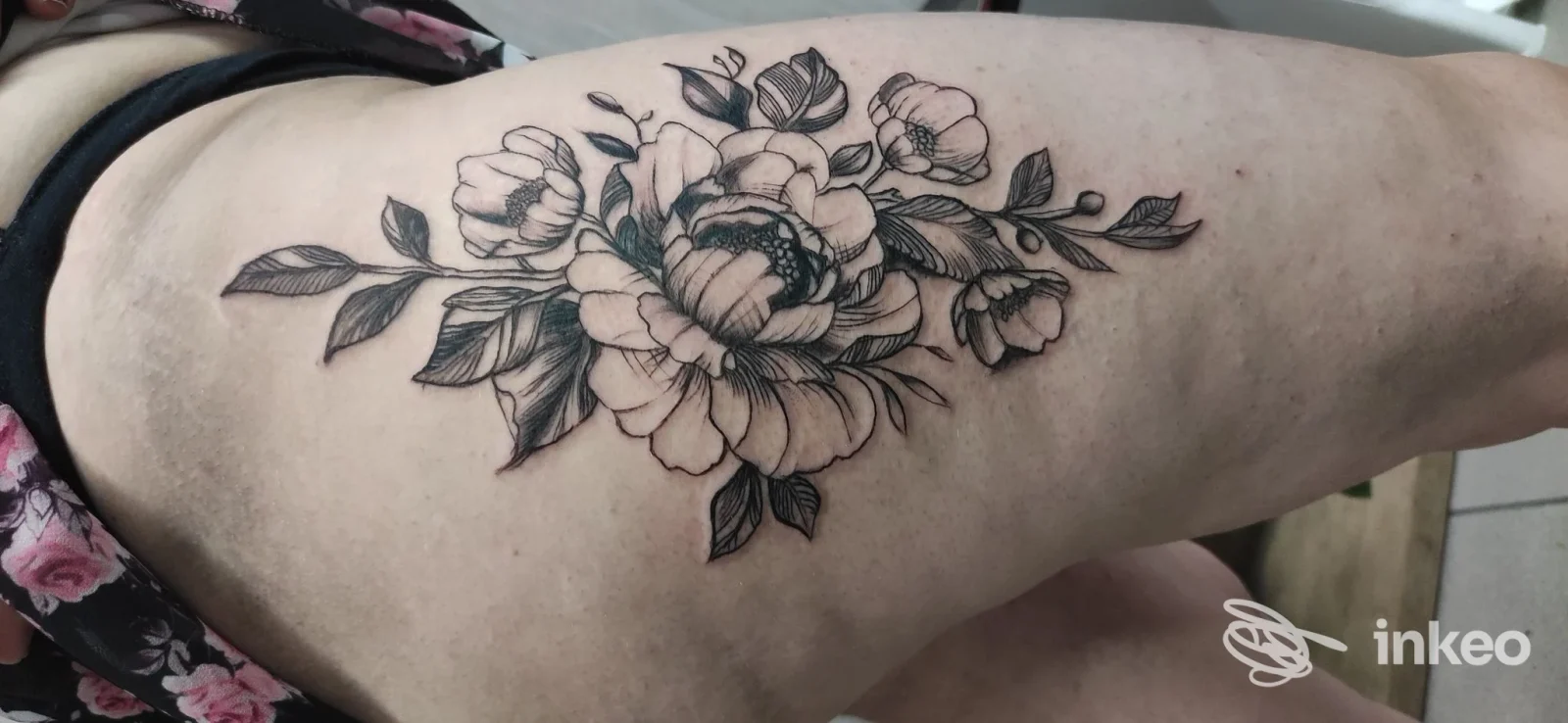 Tatuaggio floreale in nero sull'anca/coscia, fotografato presso Black Studio Tattoo Cafè a Siniscola.