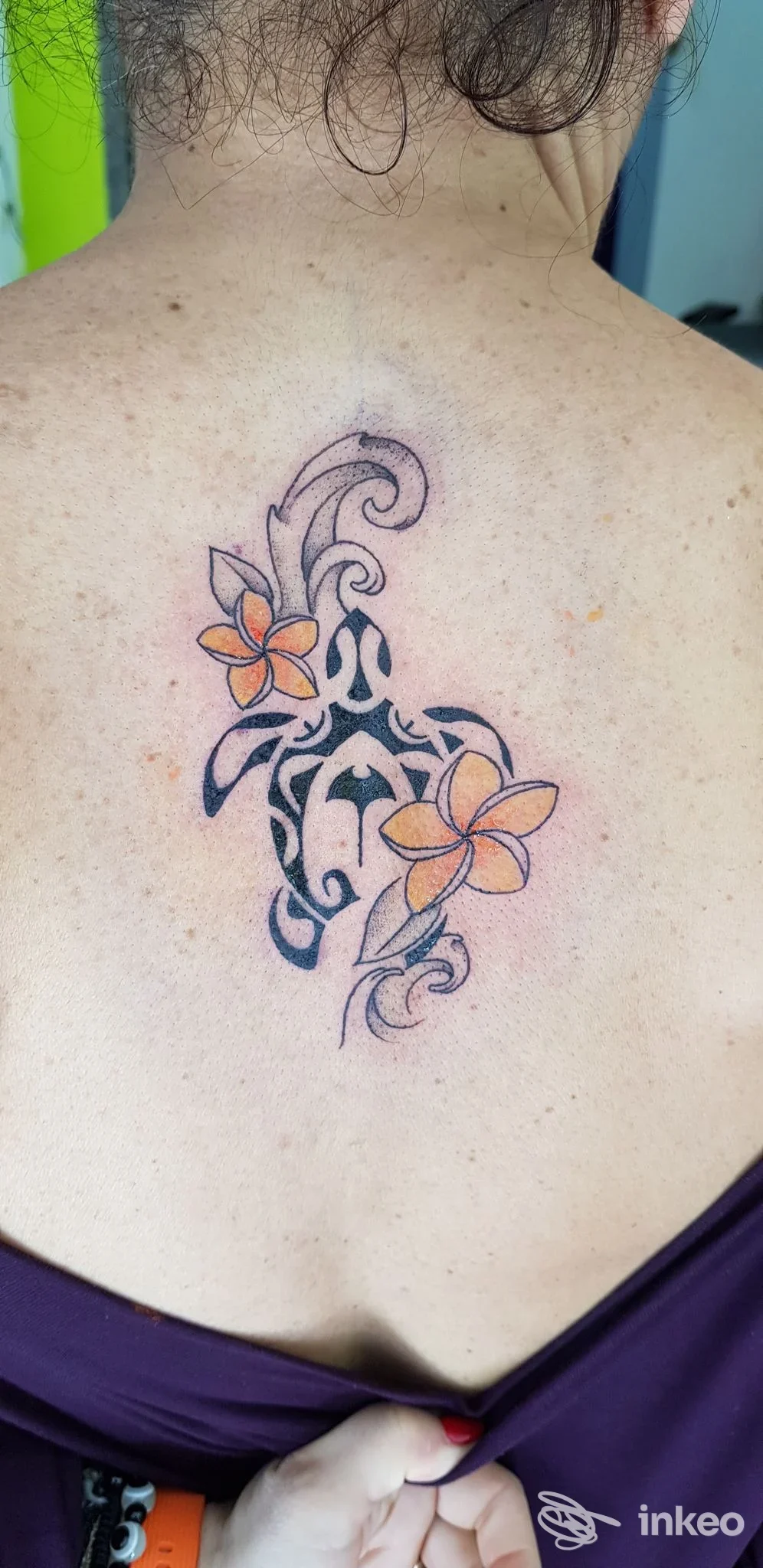 Tatuaggio tribale con fiori colorati sulla parte superiore della schiena, fotografato presso Buccaneer Tattoo Shop a Quartu Sant'Elena.