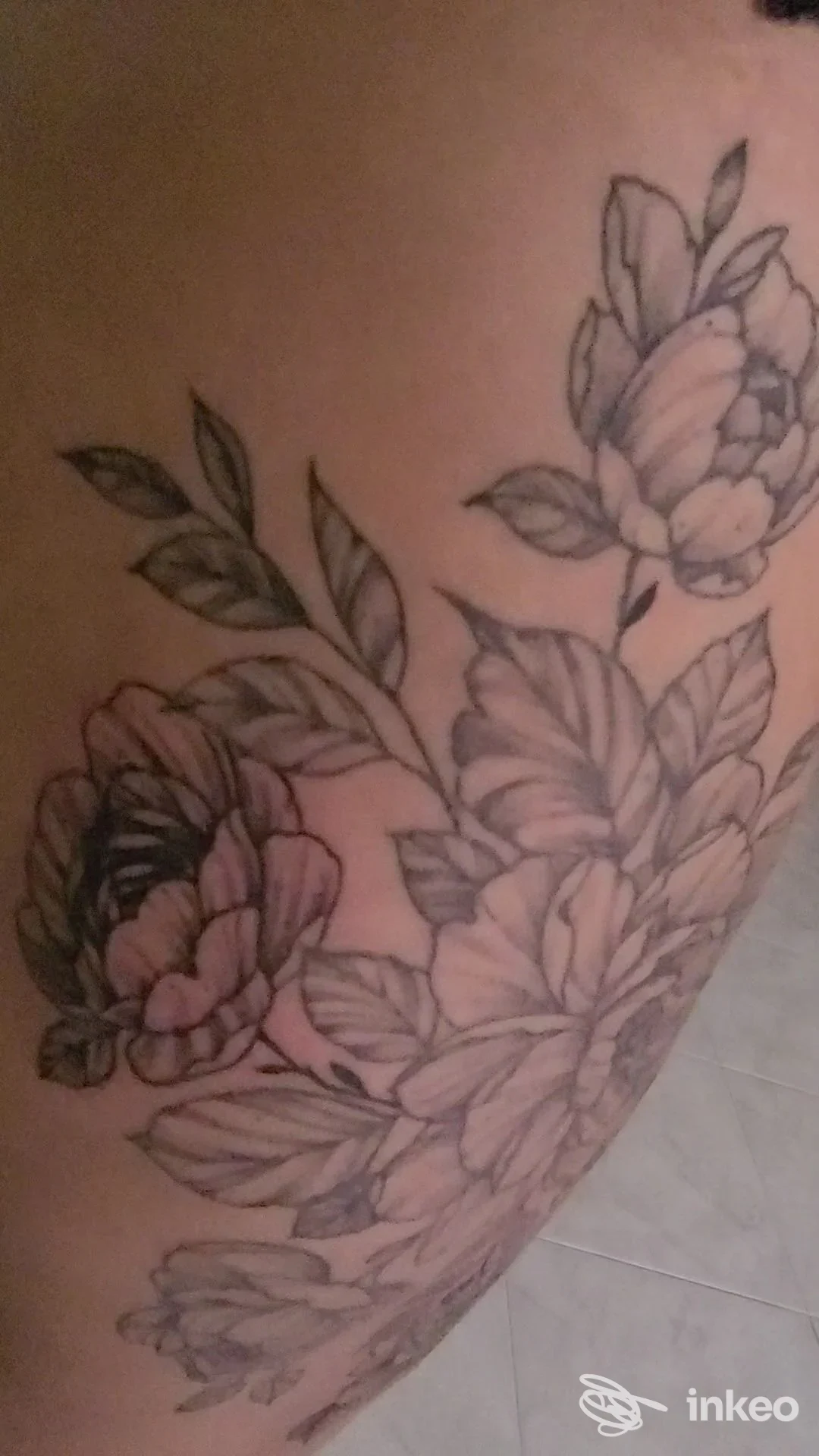 Tatuaggio floreale in nero e grigio sulla coscia, foto fornita da Custom Bull Tattoo ad Alghero.