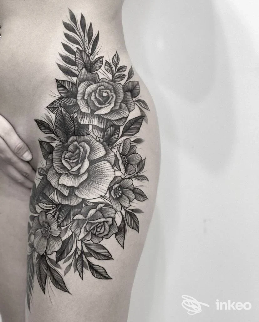 Ampia composizione floreale nera tatuata sul fianco e parte superiore della coscia, realizzata da Elegant Ink Tattoo a Monserrato.