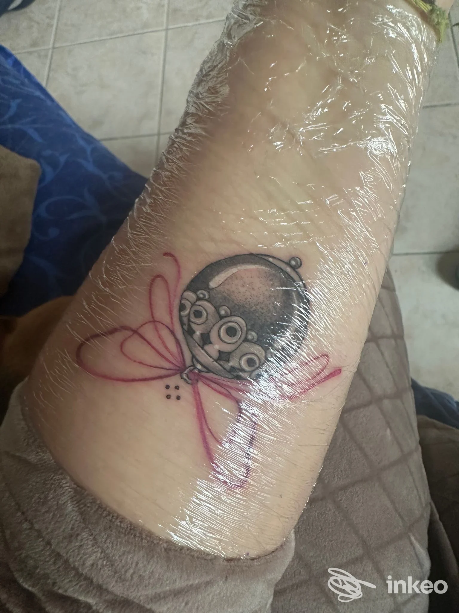 Tatuaggio recente sull'avambraccio con ornamento circolare e nastro rosa, ripreso avvolto nella pellicola - Elegant Ink Tattoo, Monserrato.