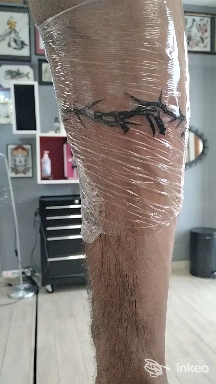 Avambraccio con tatuaggio a filo avvolgente coperto da pellicola trasparente, foto scattata nello studio Elegant Ink Tattoo a Monserrato.