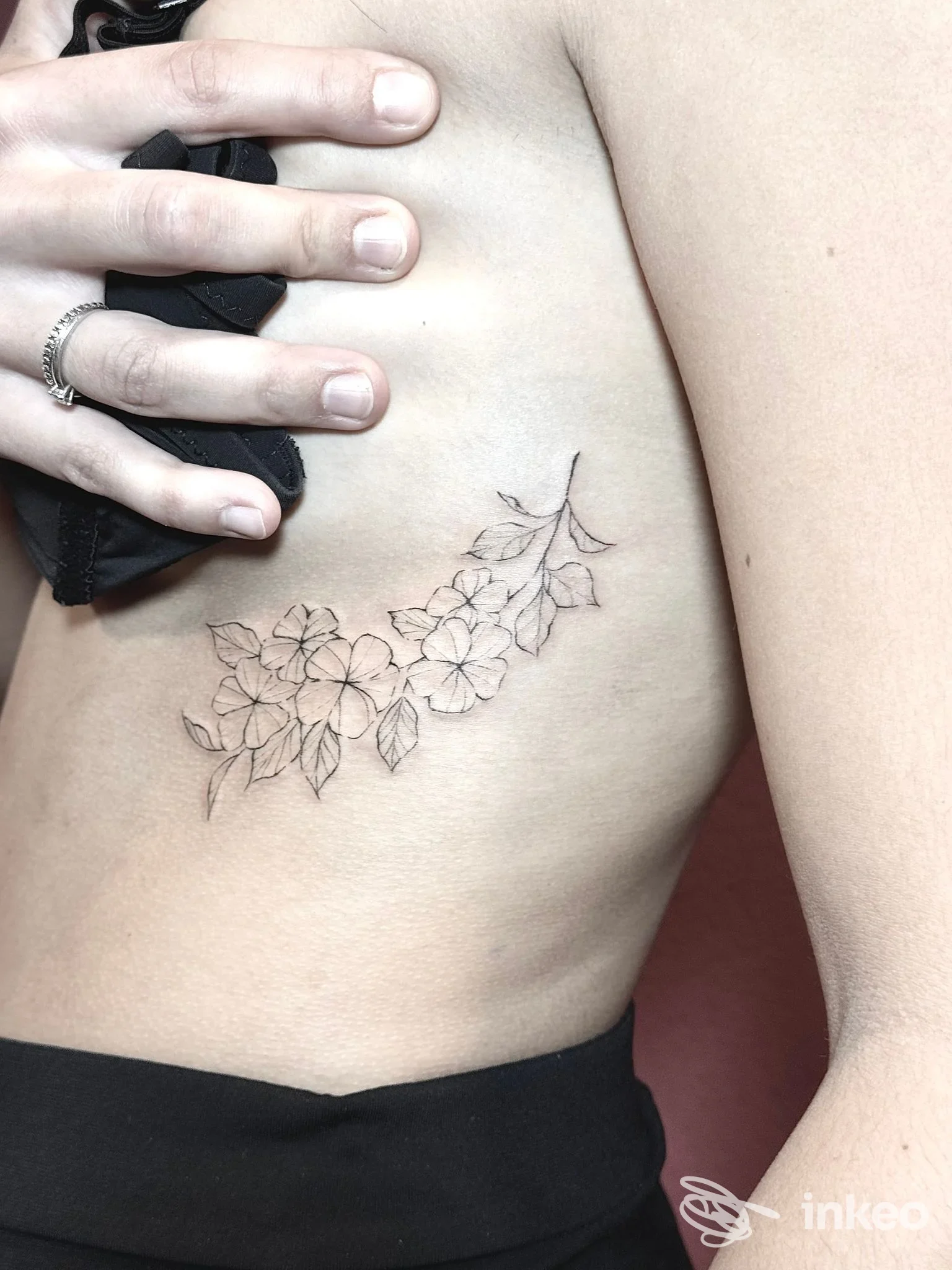Tatuaggio floreale lineare sulla zona costale di una persona, realizzato da Forgia Custom Tattoo ad Alghero, in interno.