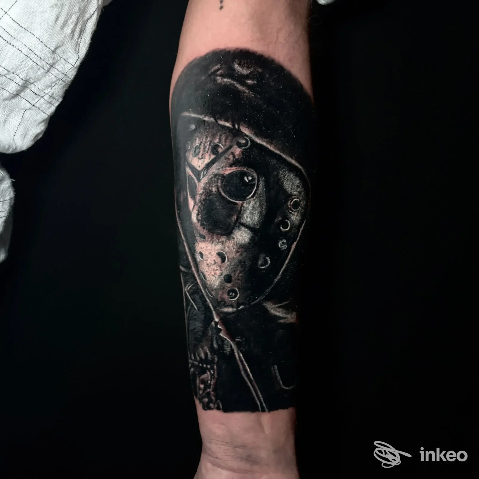 Tatuaggio realistico scuro di una maschera su avambraccio, foto fornita da Ginevra Tattoo Ink, Sassari.