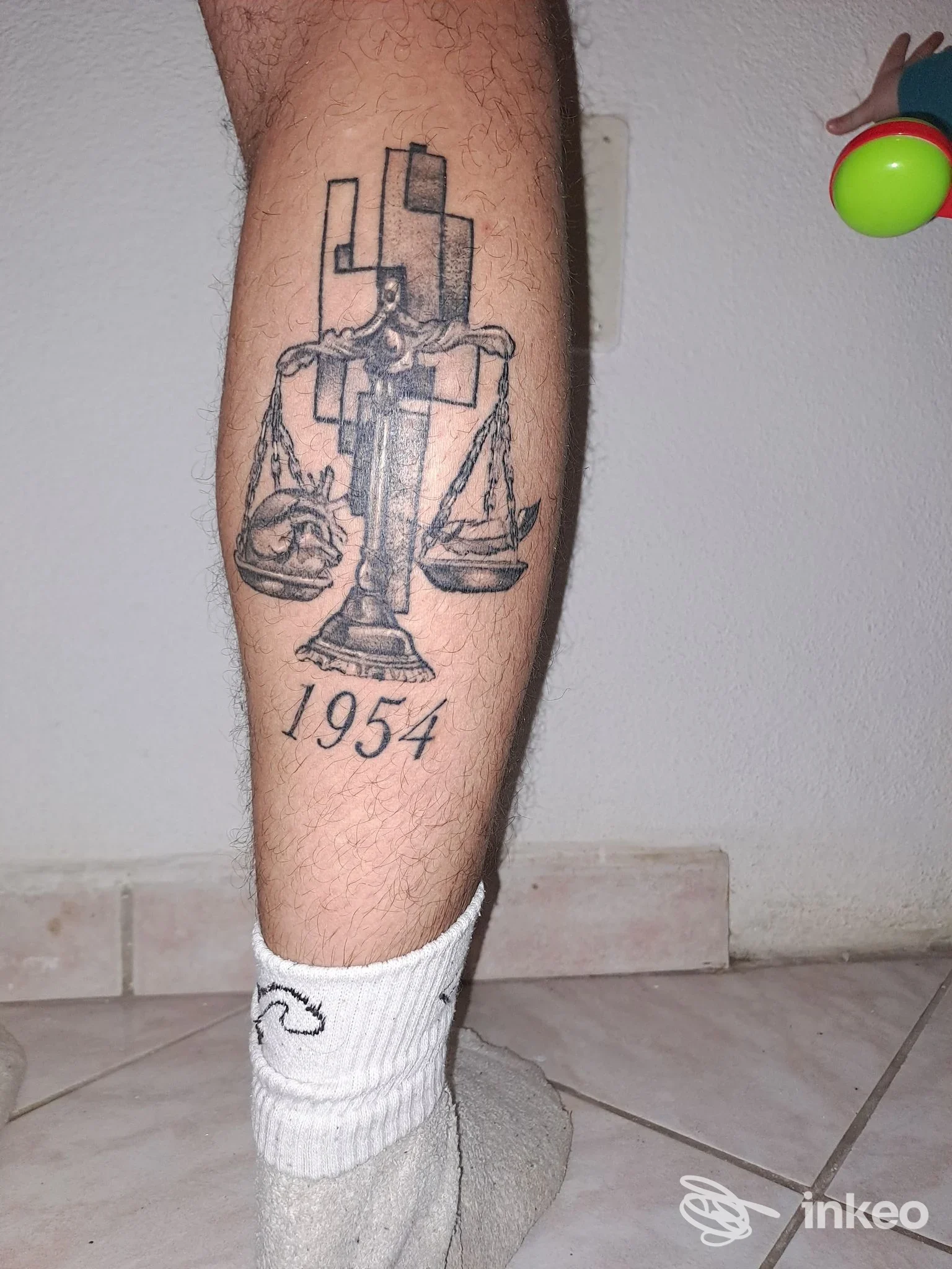 Tattoo sul polpaccio raffigurante una bilancia con il numero 1954, foto inviata per Giofoe TATTOO Giorgio Forlano, La Caletta.