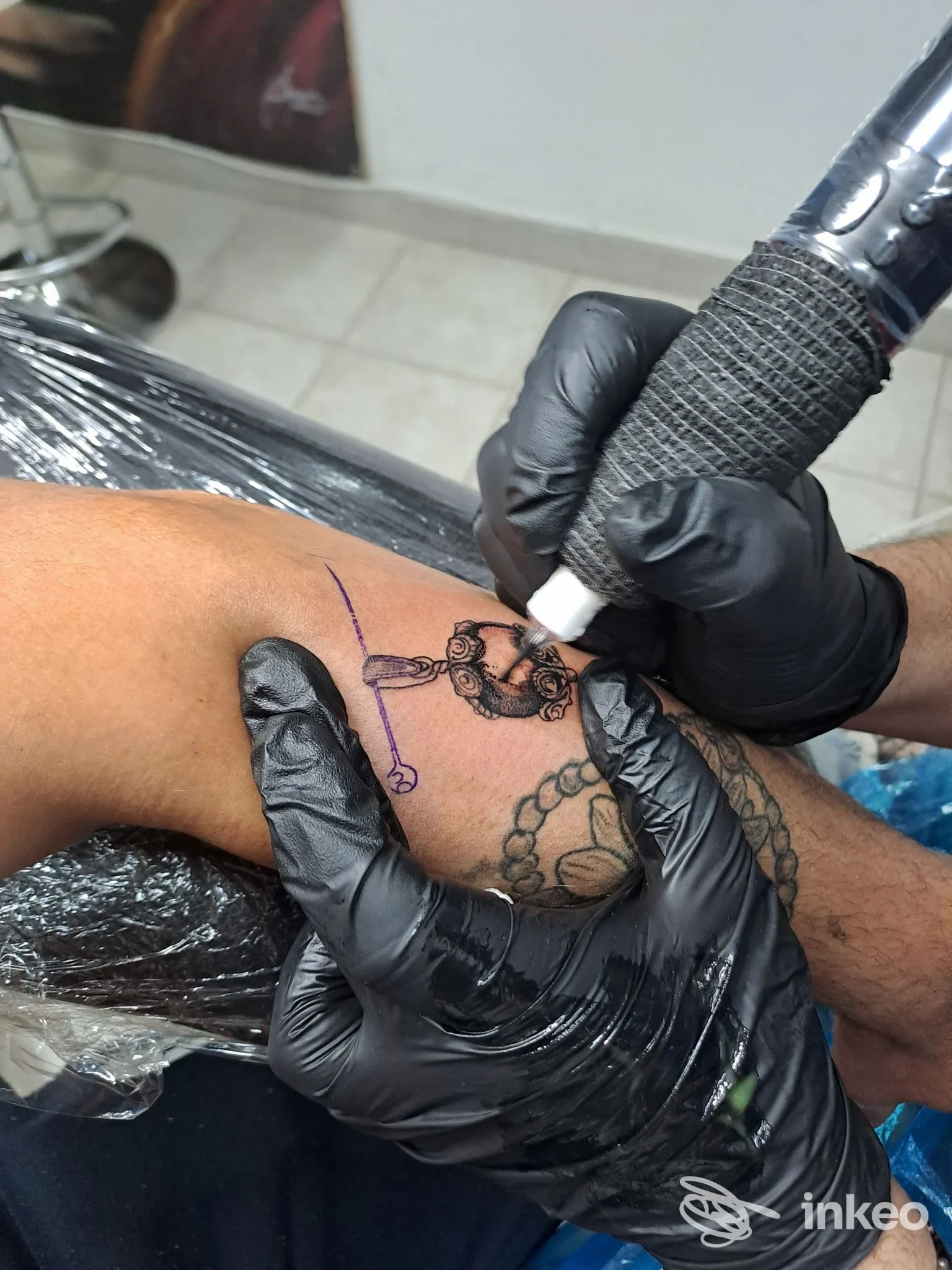 Tatuatore al lavoro sul dorso della mano, rifinitura di un tatuaggio presso Giofoe TATTOO a La Caletta.