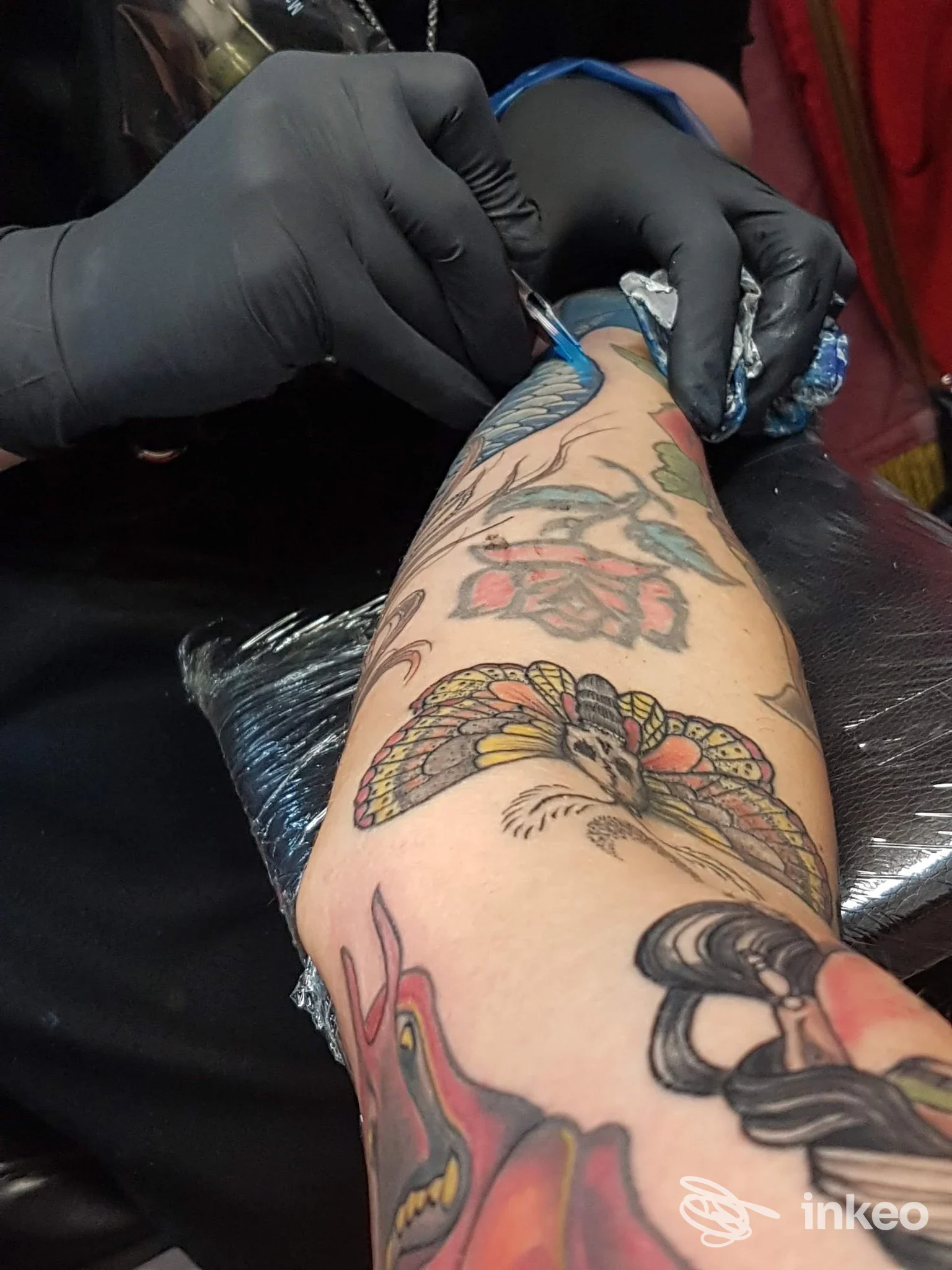 Operatore al lavoro su un avambraccio tatuato, foto fornita da HardCoreTattoo a Cagliari, dettagli colorati sul braccio in primo piano.