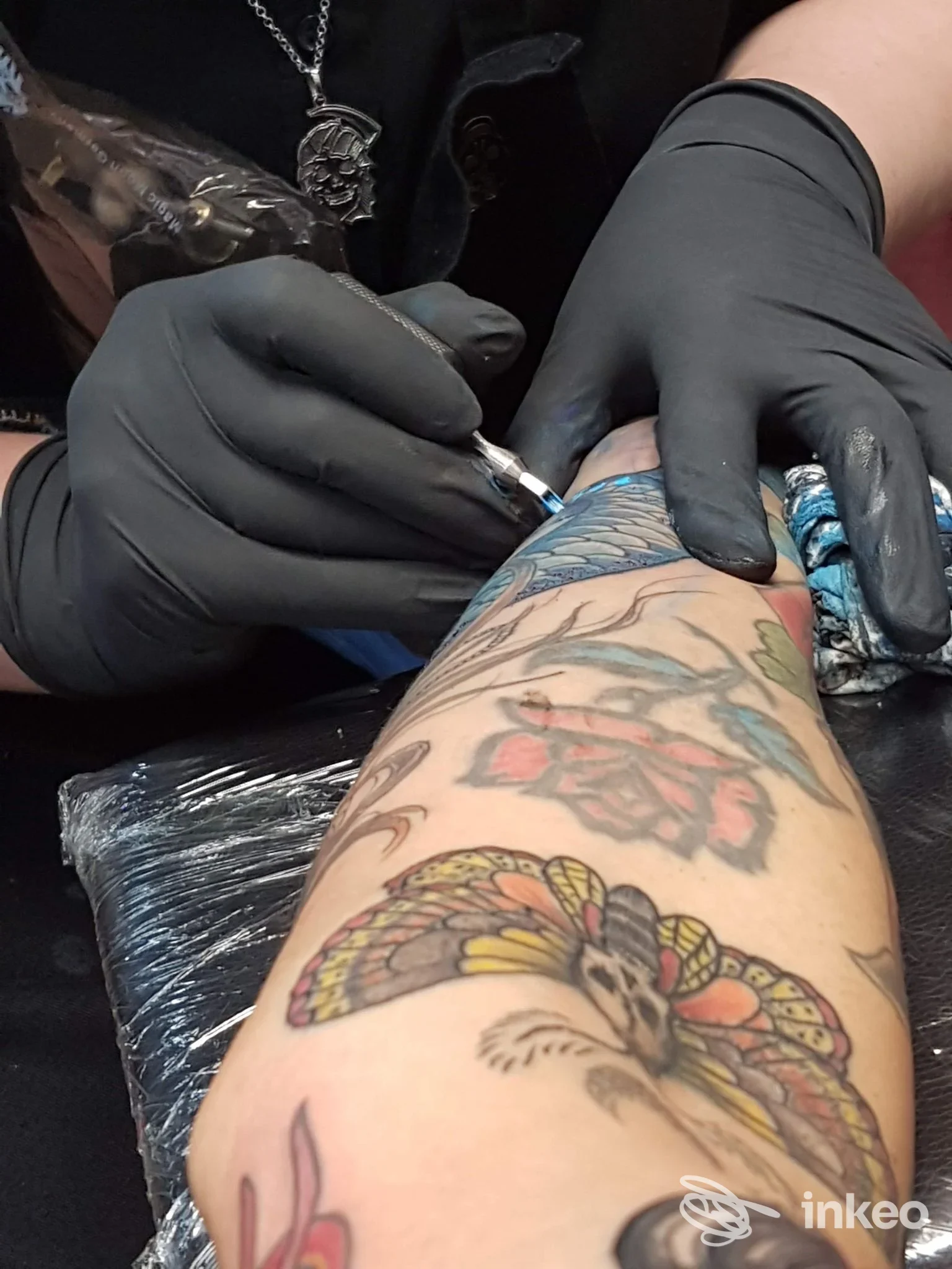 Artista di HardCoreTattoo a Cagliari che esegue un tatuaggio a colori sul'avambraccio di un cliente, primo piano sul gesto di tatuare.