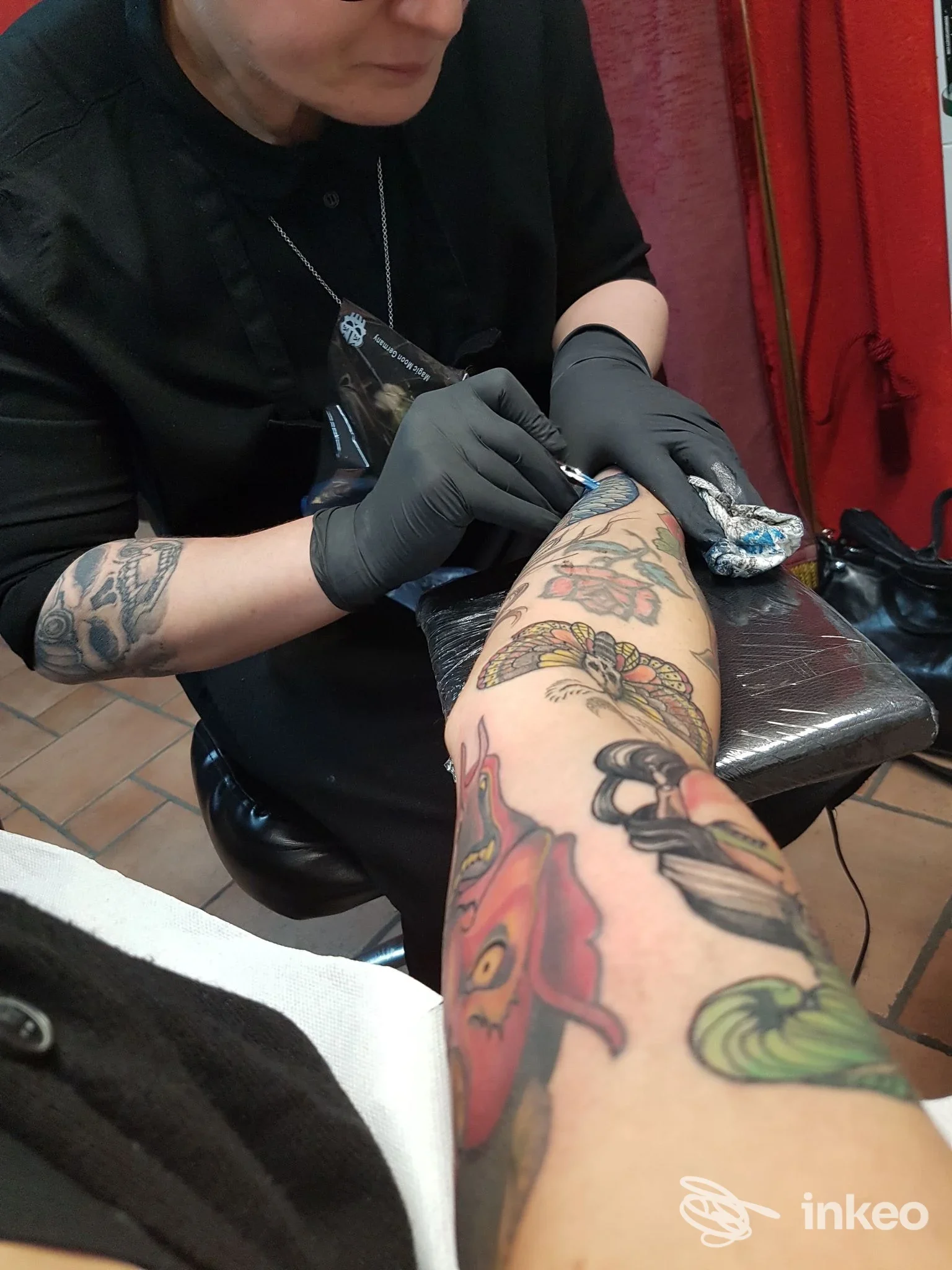 Artista di HardCoreTattoo a Cagliari al lavoro su un avambraccio tatuato, vista ravvicinata dello studio durante la sessione.