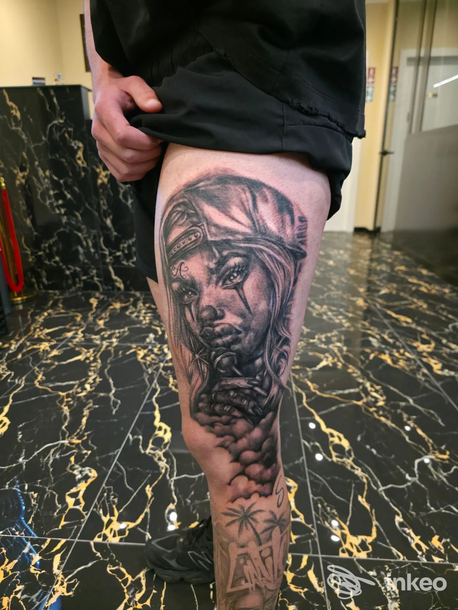 Tatuaggio realistico in bianco e nero su coscia con volto femminile e rosario; foto inviata da INKIOSTRO studio tatuaggi, Cagliari.
