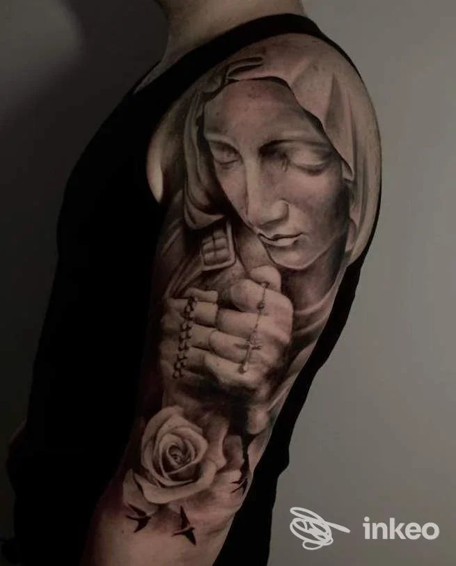 Tatuaggio realistico a mezza manica sul braccio superiore: Madonna con rosario e rosa. Ink Lab Tattoo Studio, Oristano.