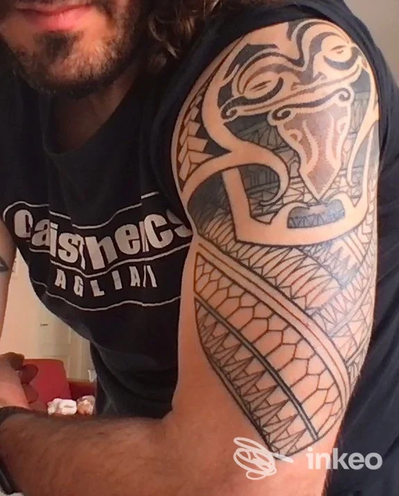 Primo piano di un tatuaggio tribale che copre il braccio superiore di un uomo, foto per portfolio presso MILLY MACIS Inkanto Tattoo a Cagliari, dettaglio dell'inchiostro.