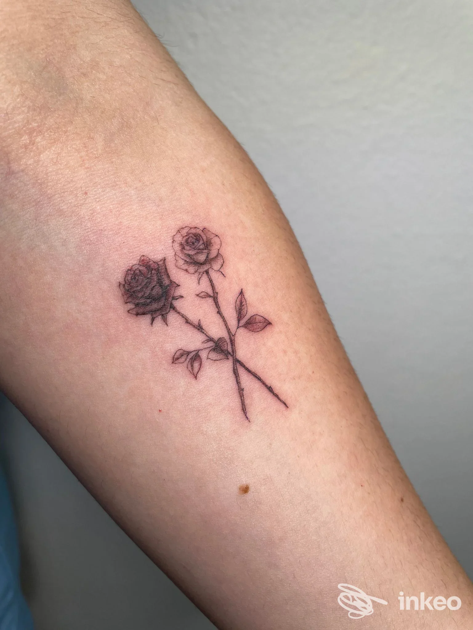 Due rose stilizzate tatuate sull'avambraccio con linee sottili e ombreggiature delicate. MS tattoo artist, Quartucciu.