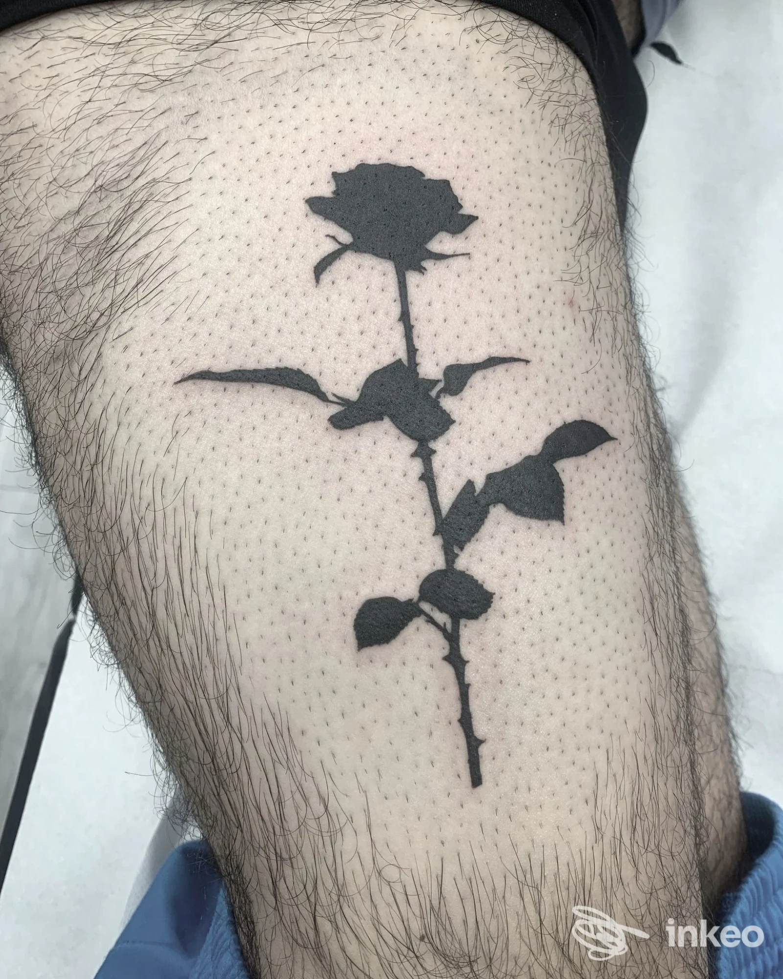 Tatuaggio blackwork a forma di rosa in silhouette su coscia fotografato da Mad Ink Tattoo, Simaxis.